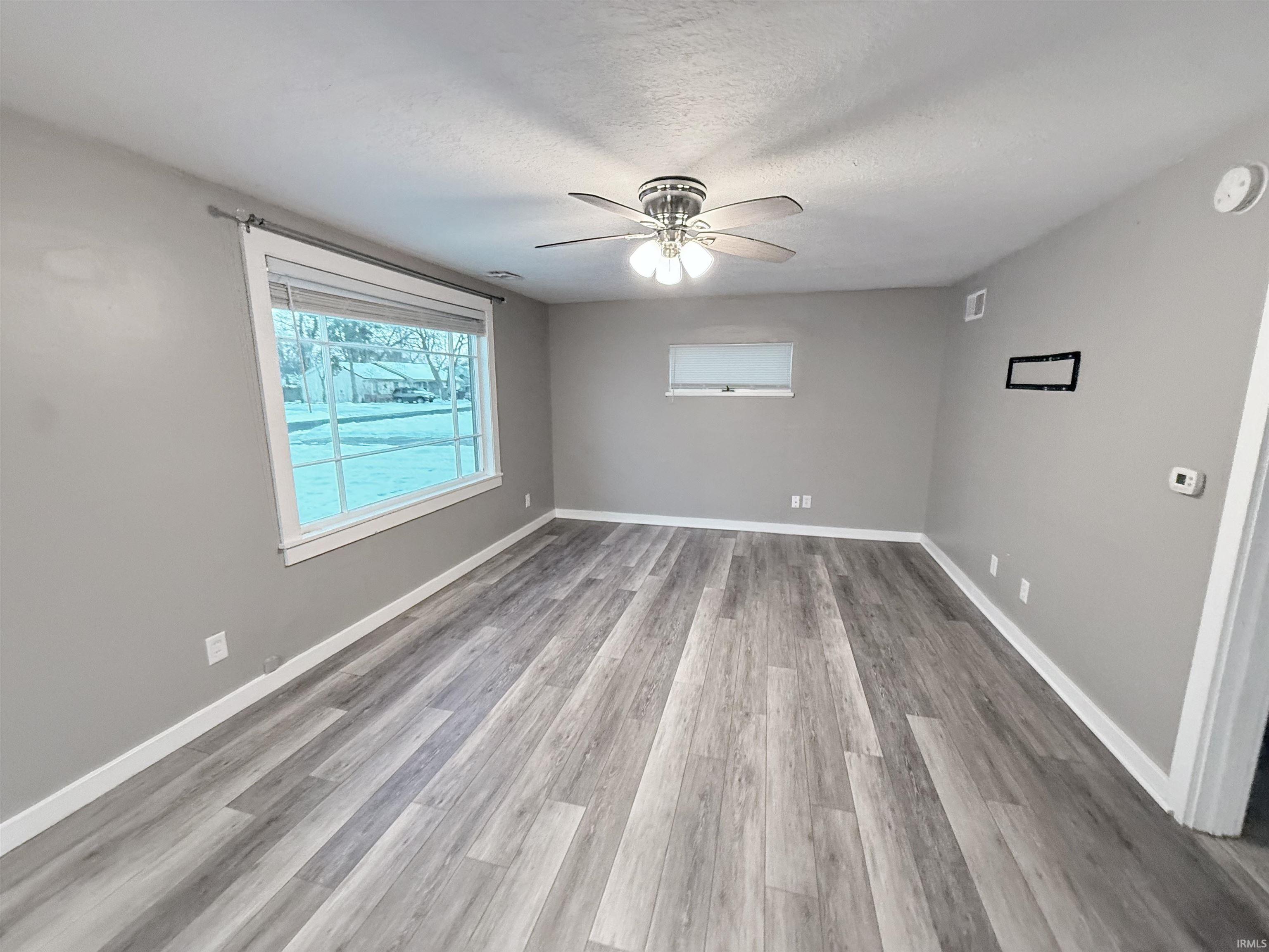 Spare room featuring light wood finished floors, a textured ceiling, and a ceiling fan