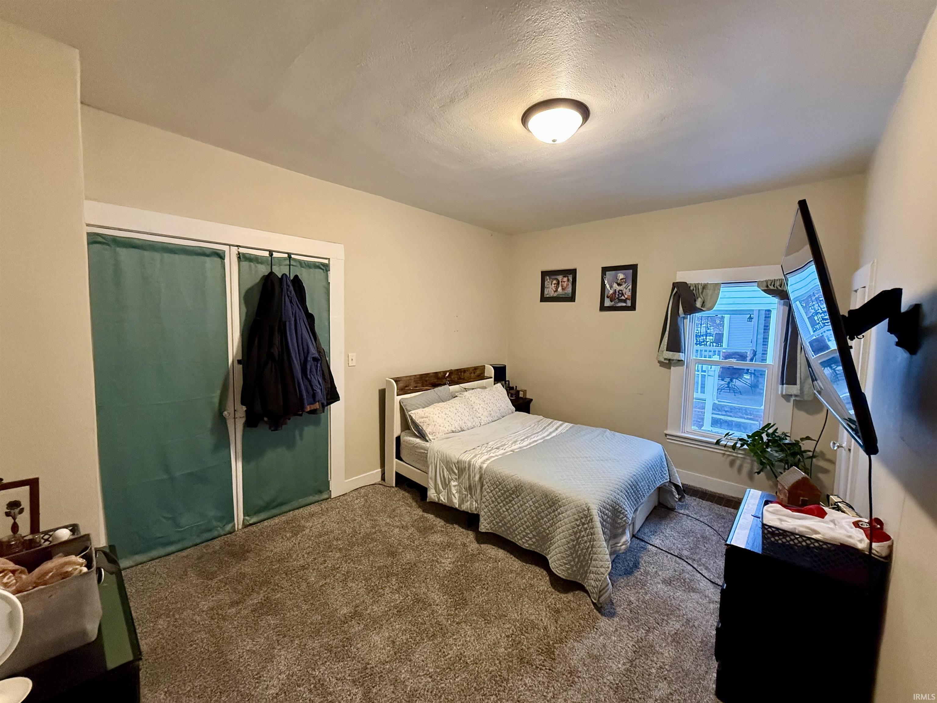 Bedroom with carpet, a closet, and a textured ceiling