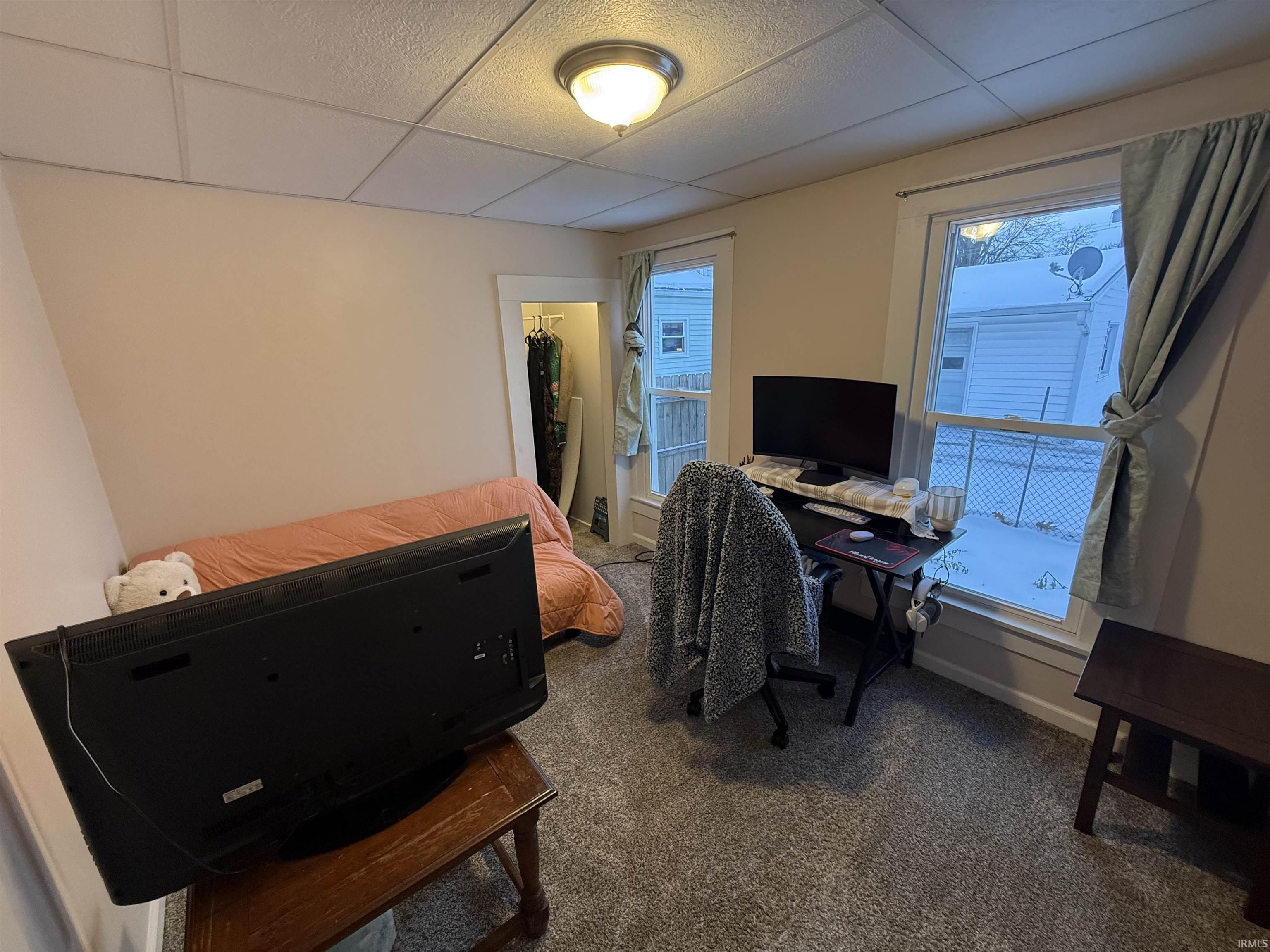 Home office with carpet flooring and a drop ceiling