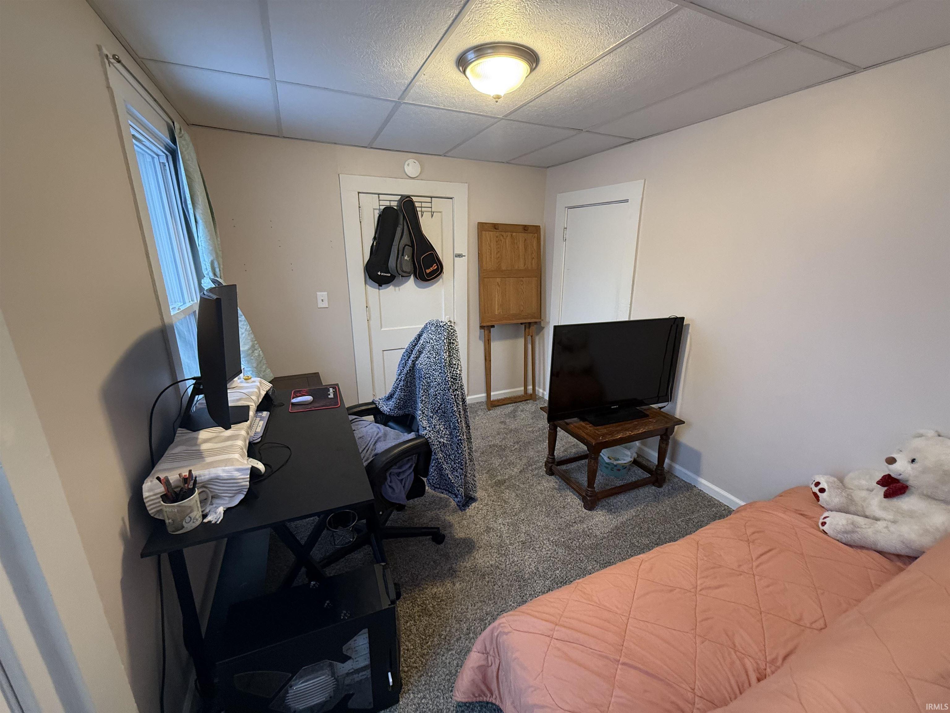 Bedroom featuring a drop ceiling, an office area, carpet floors, and a closet