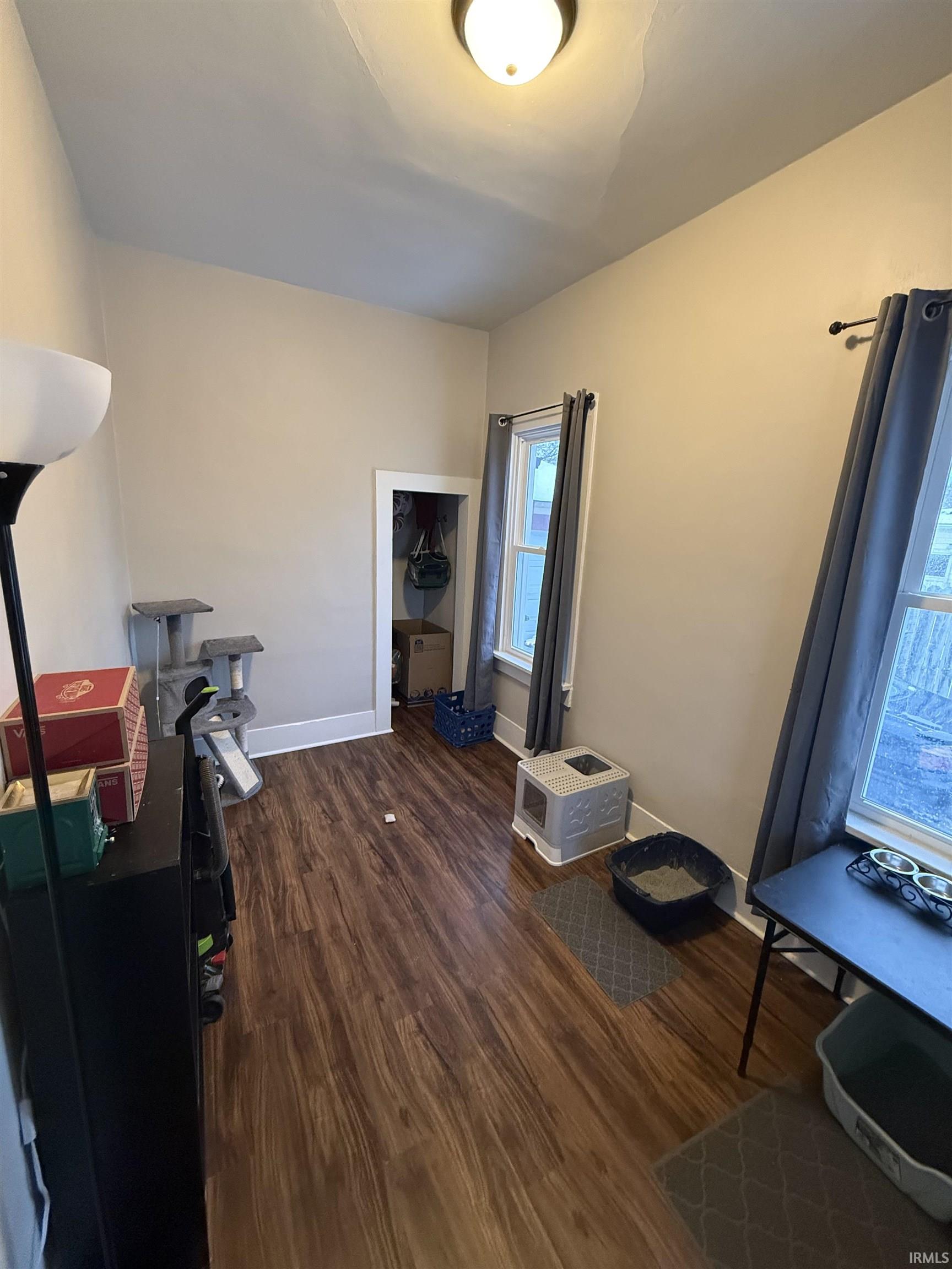 Miscellaneous room with dark wood-type flooring and baseboards