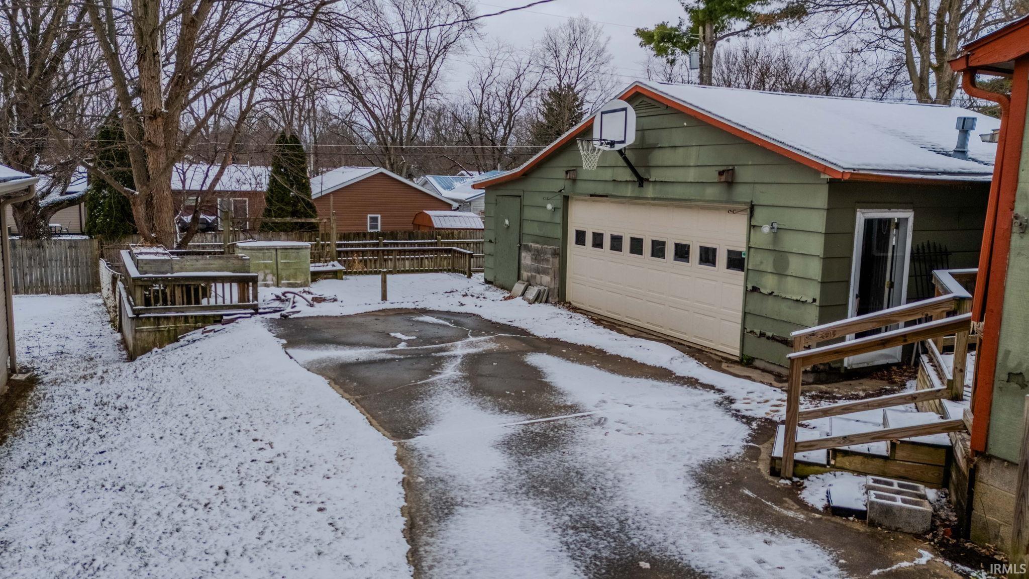 View of snowy exterior featuring an outbuilding and a detached garage