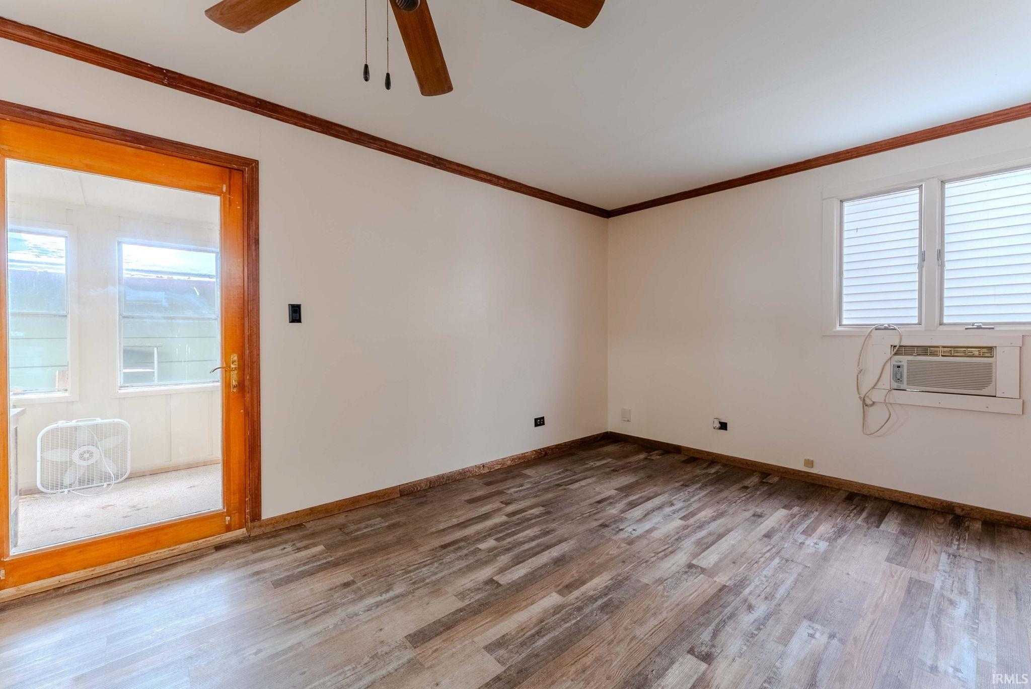 Spare room featuring light wood-style flooring, ornamental molding, and a ceiling fan