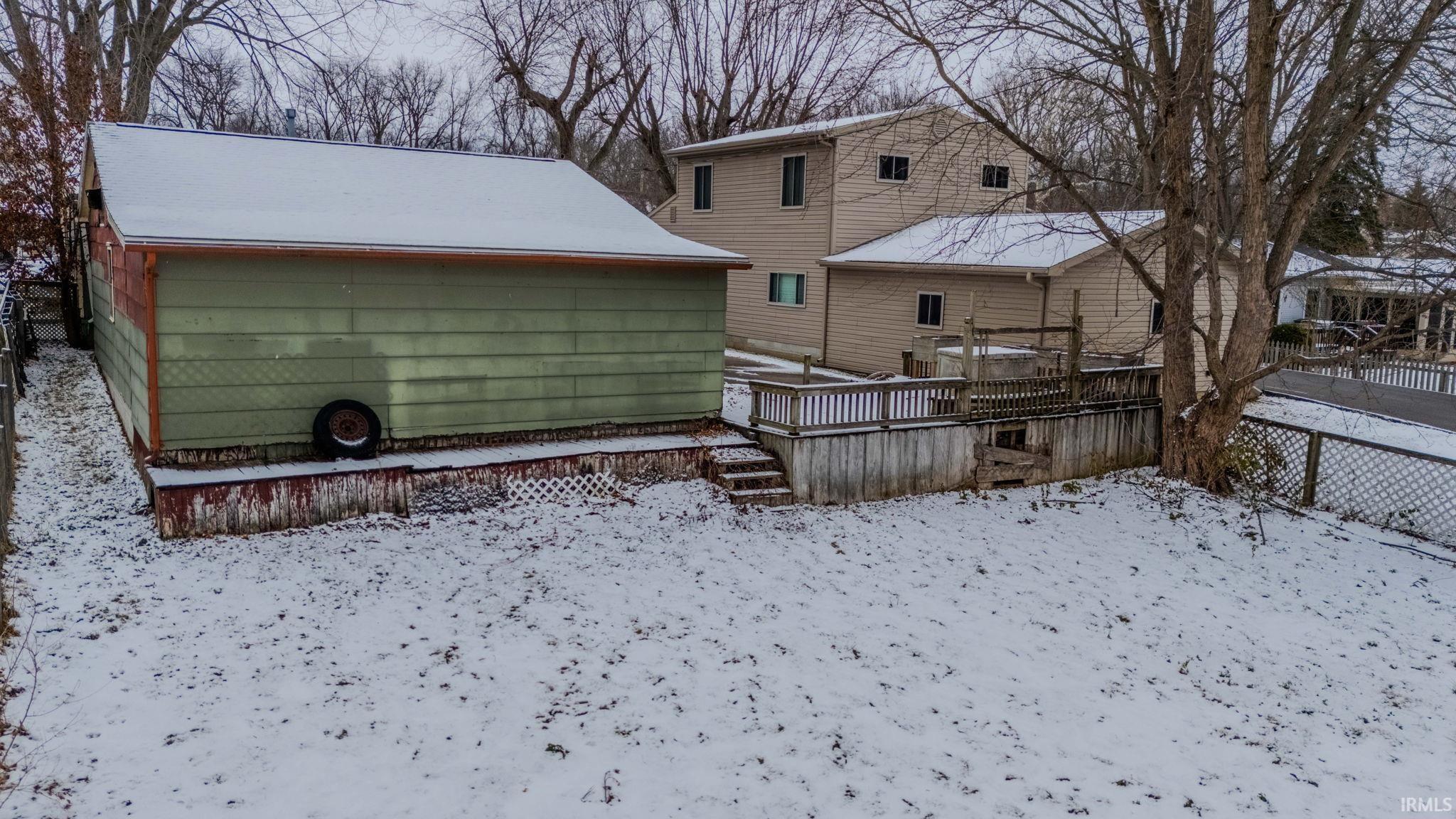 Snow covered back of property with a deck