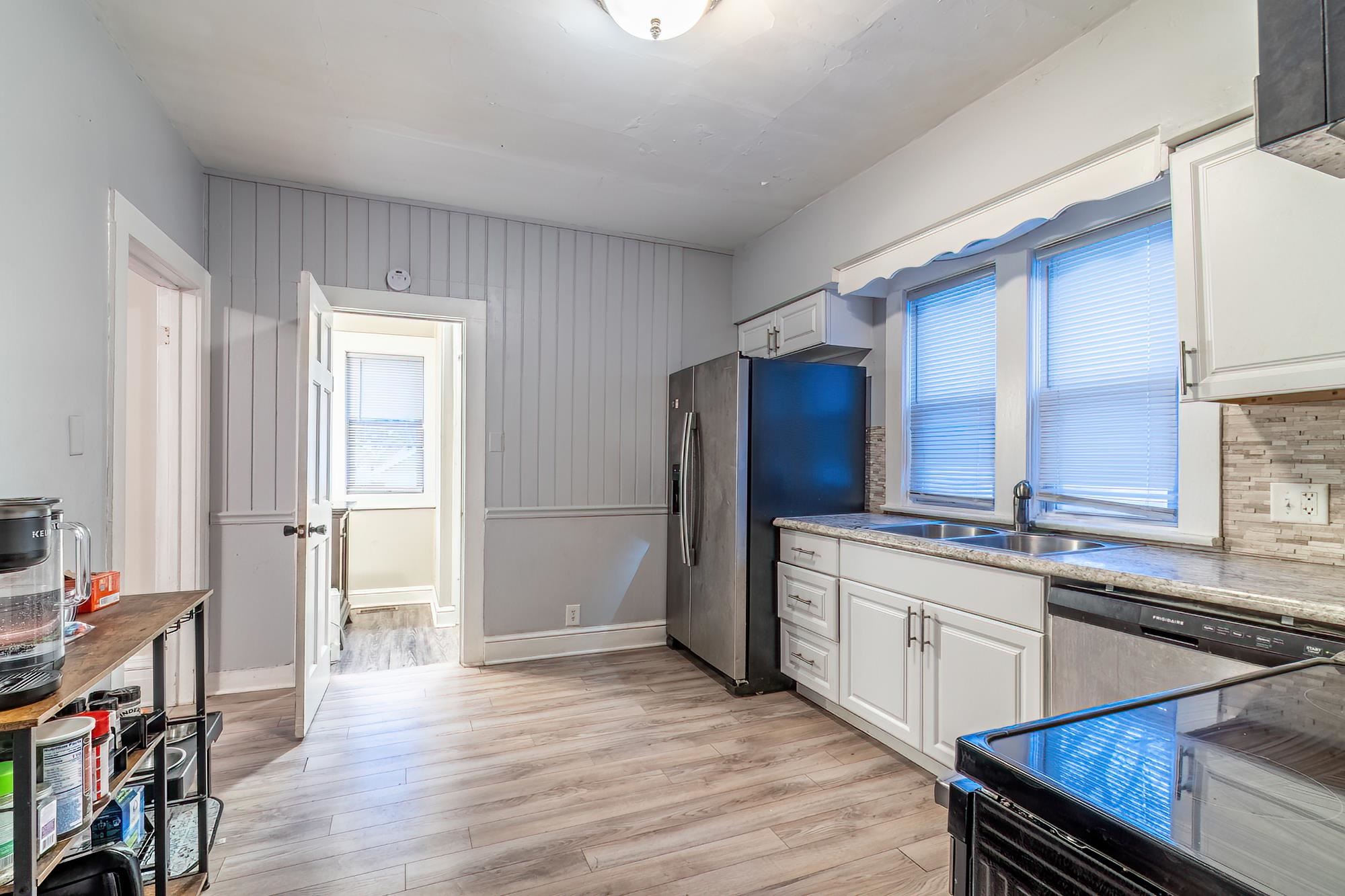 Kitchen featuring white cabinets, light wood-type flooring, stainless steel appliances, and light stone countertops