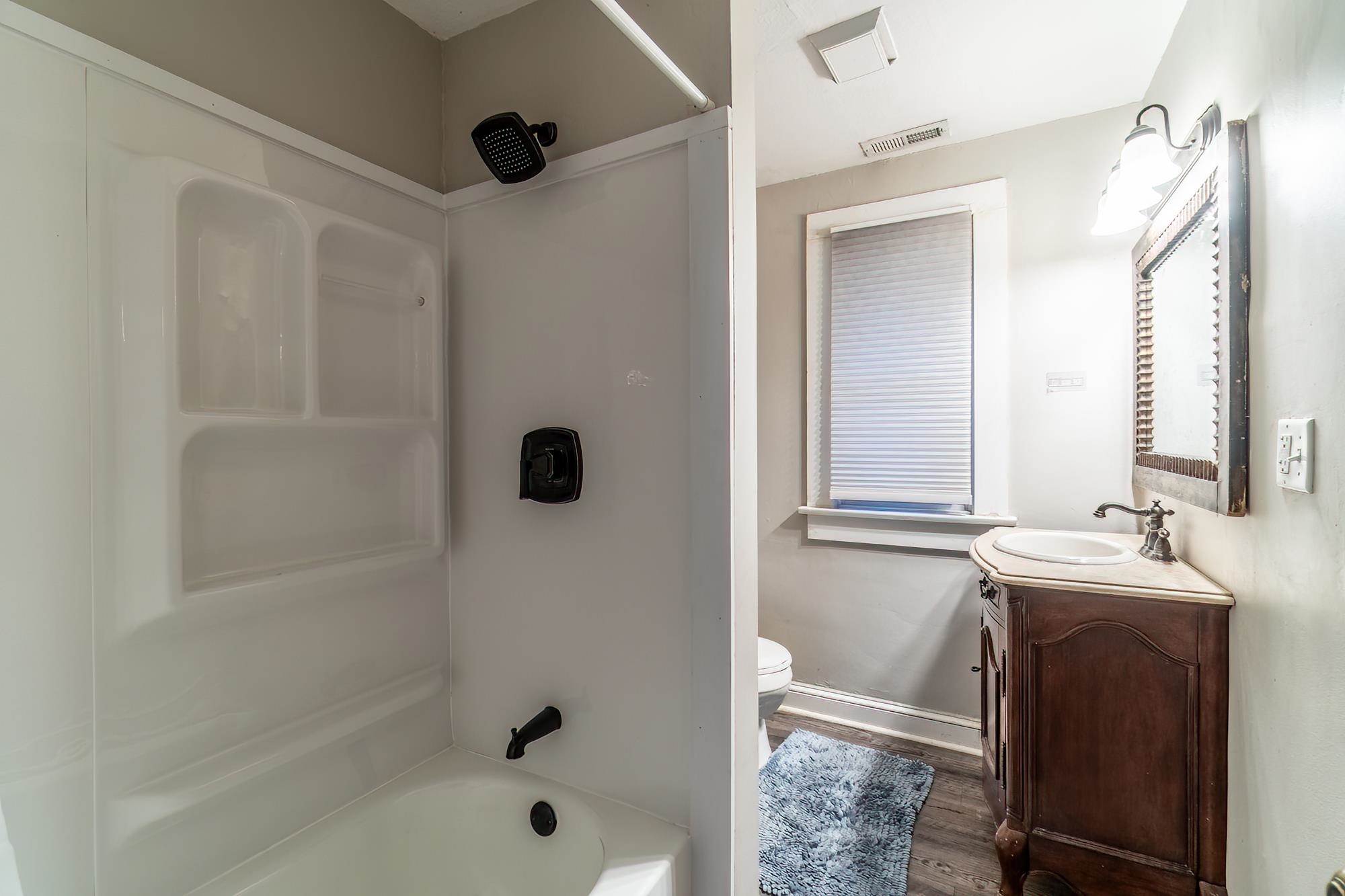 Full bathroom with vanity, shower / bath combination, and dark wood-style floors