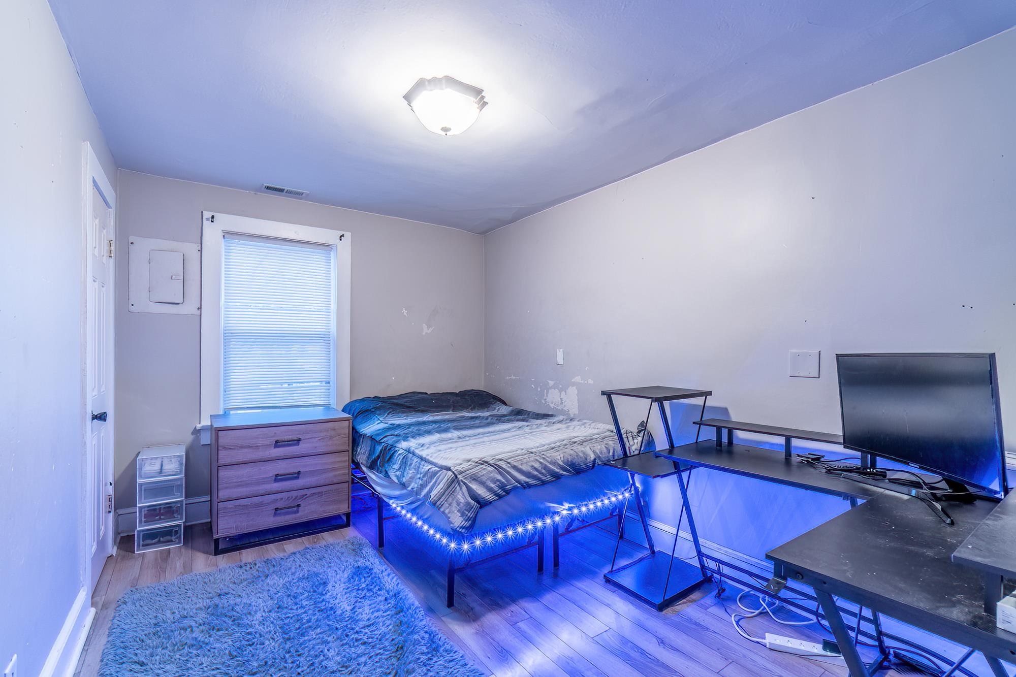 Bedroom with an office area, wood finished floors, and electric panel