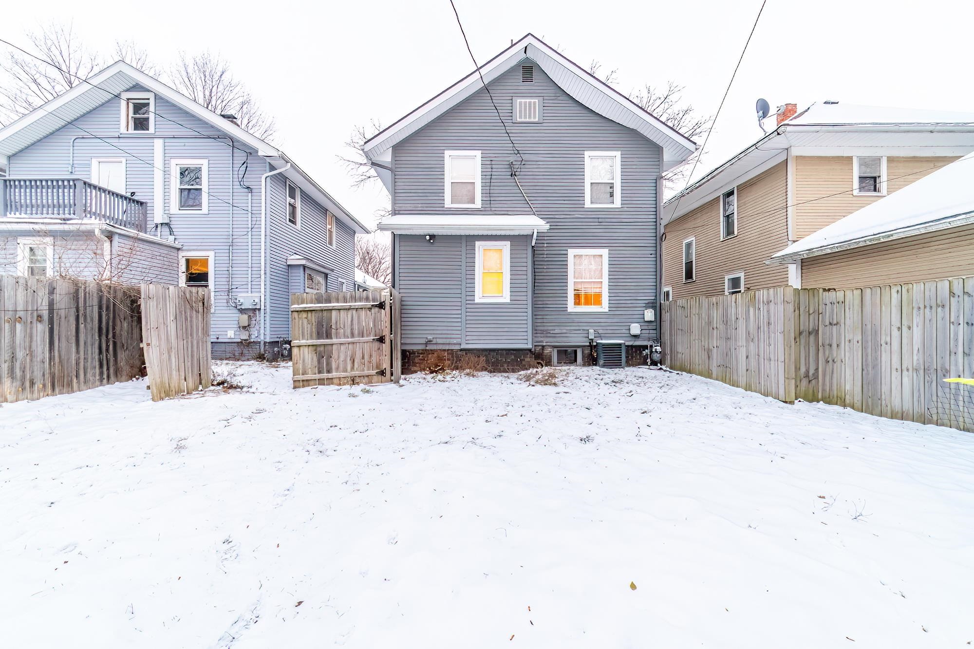 Snow covered house with a fenced backyard