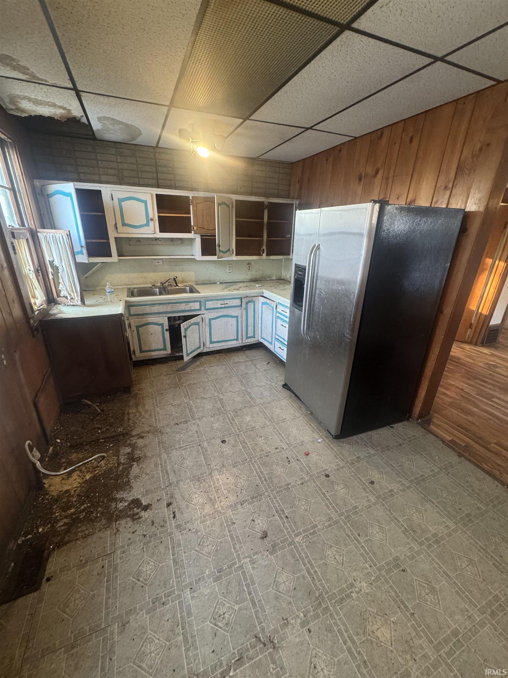 Kitchen with a paneled ceiling, light floors, open shelves, stainless steel fridge with ice dispenser, and light countertops