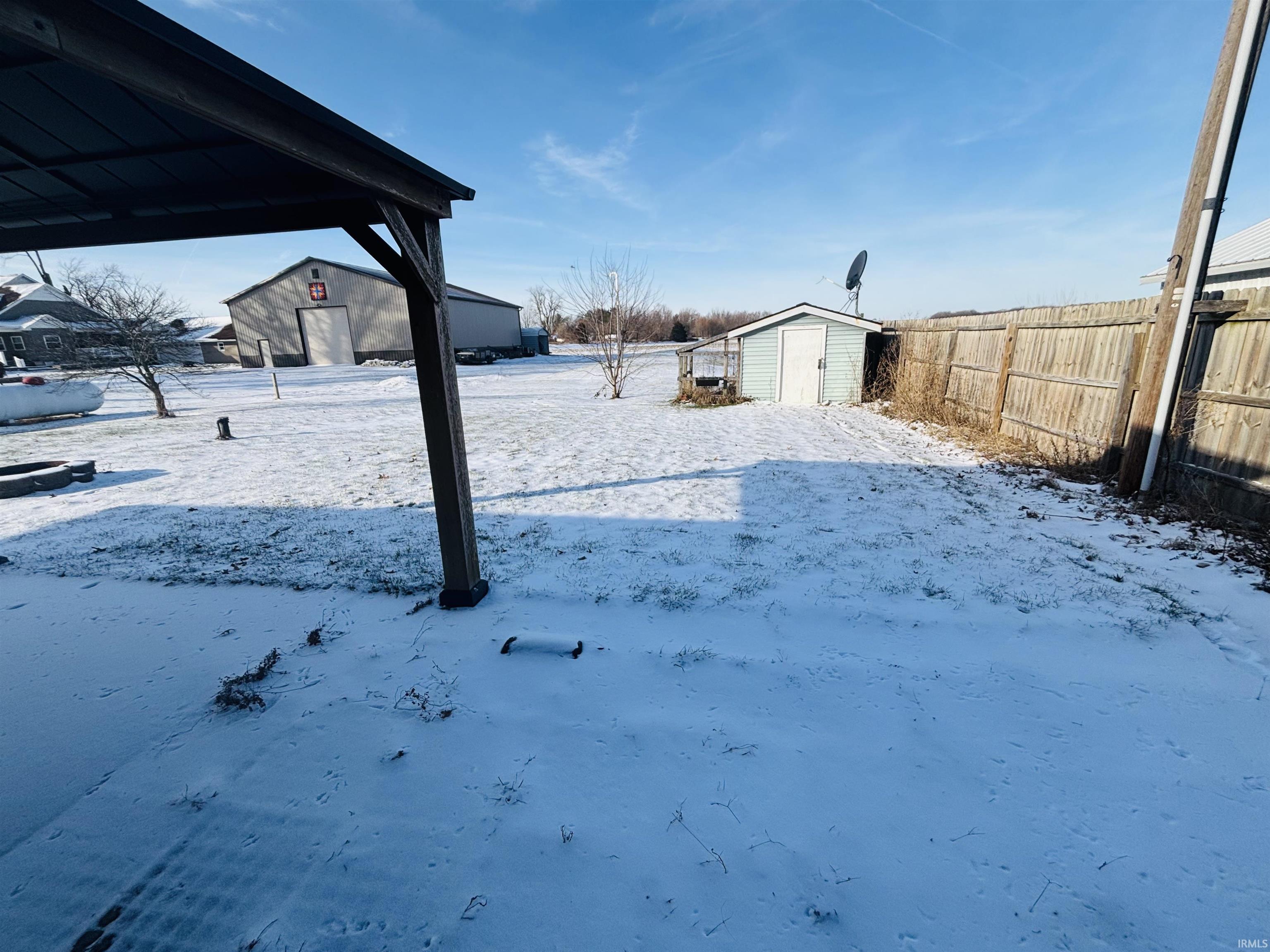 Yard layered in snow featuring a storage shed and a fenced backyard
