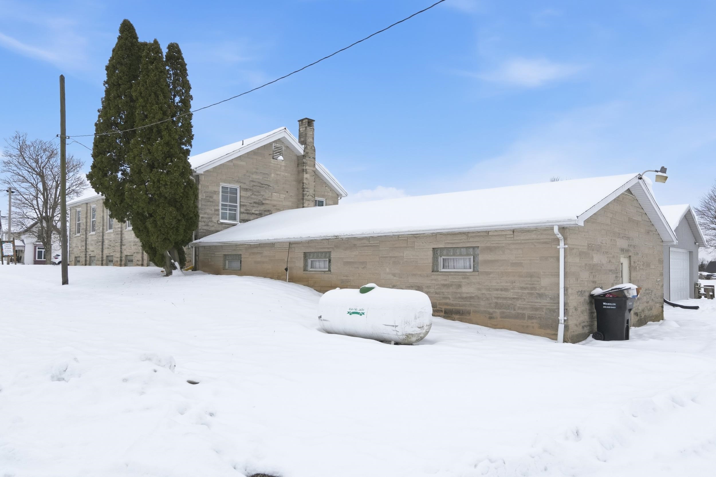 Snow covered rear of property with a chimney