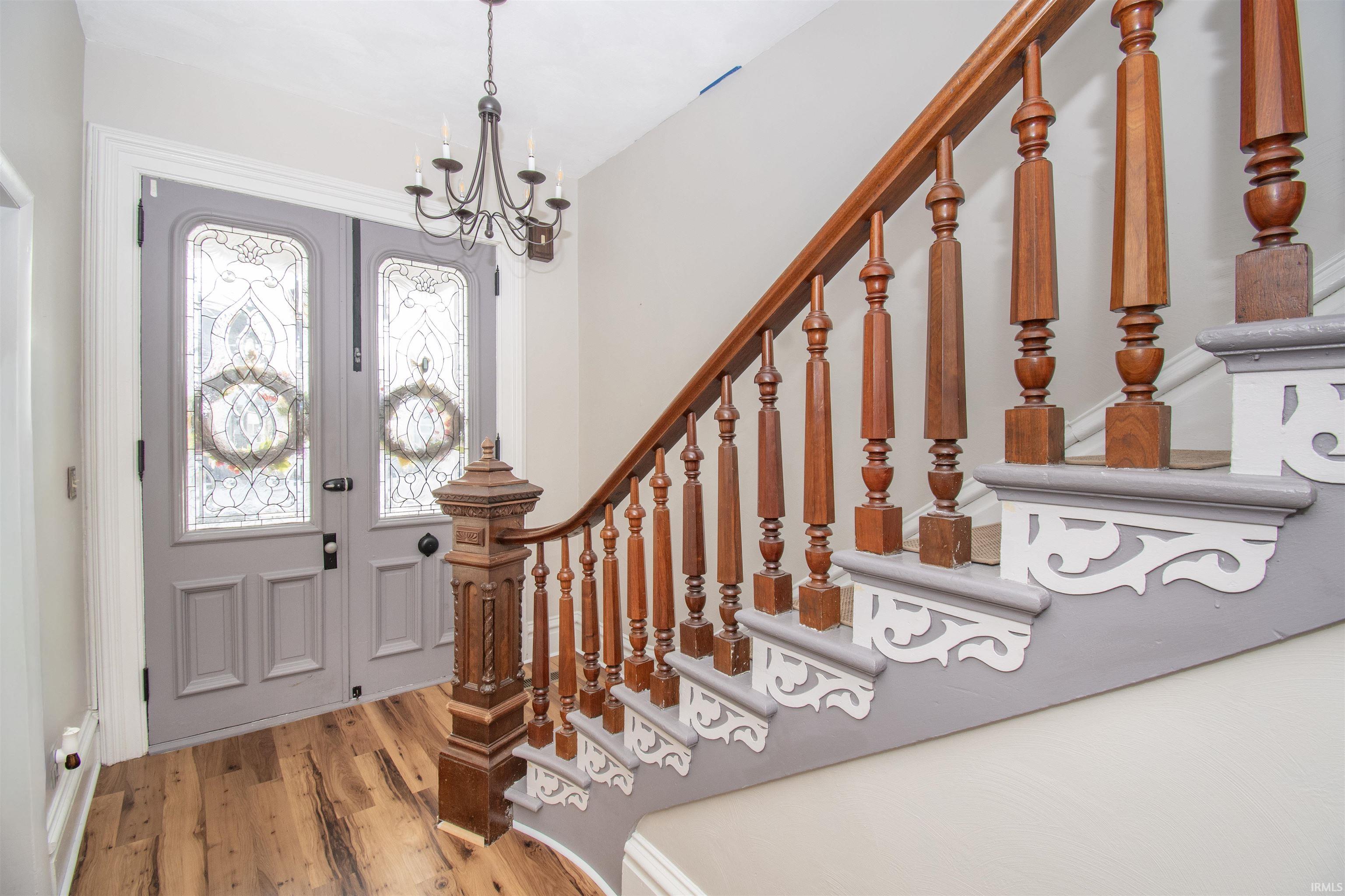 Foyer entrance featuring stairway, wood finished floors, and a chandelier