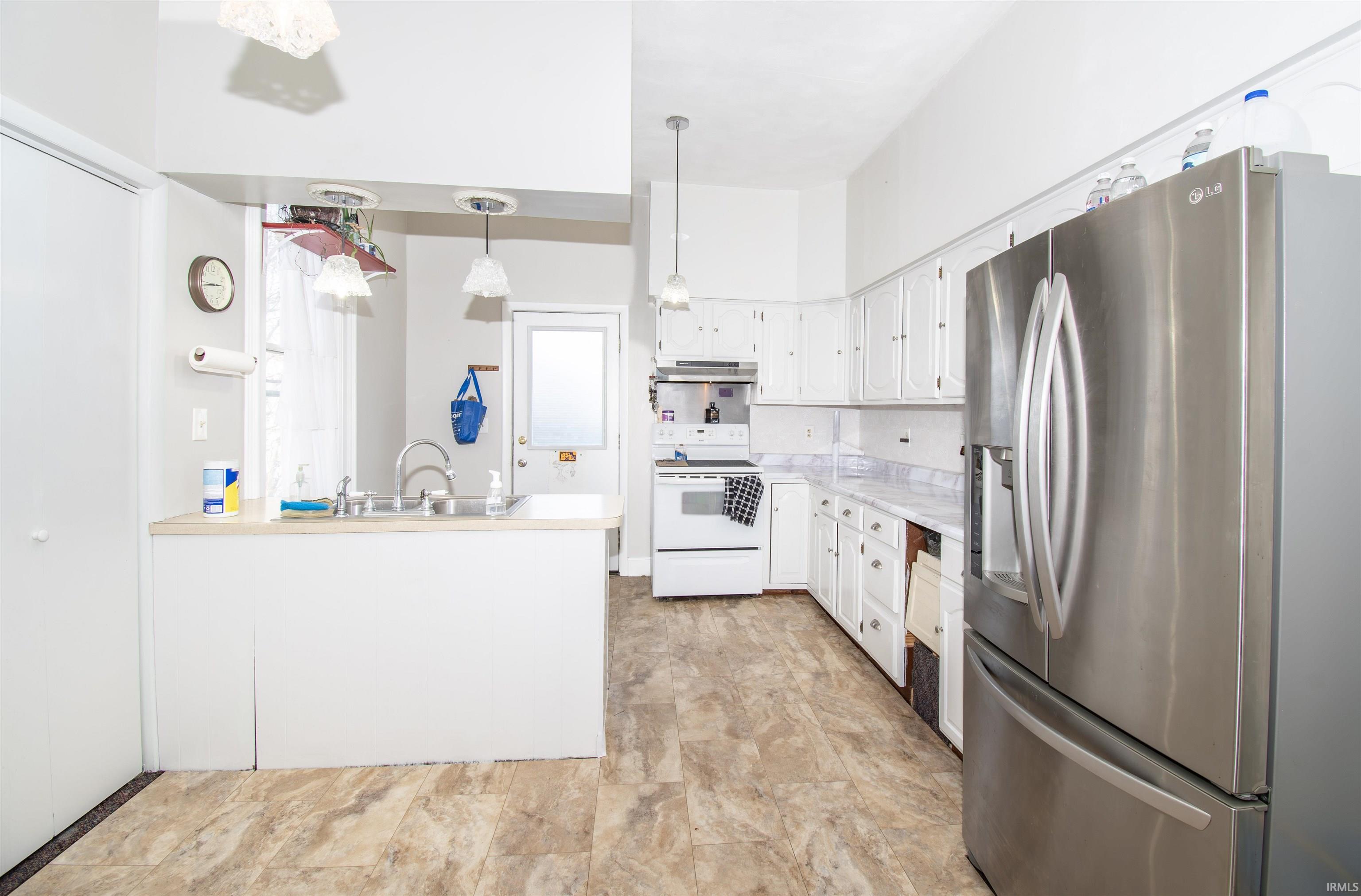 Kitchen with stainless steel fridge with ice dispenser, white cabinets, light countertops, white electric range, and pendant lighting