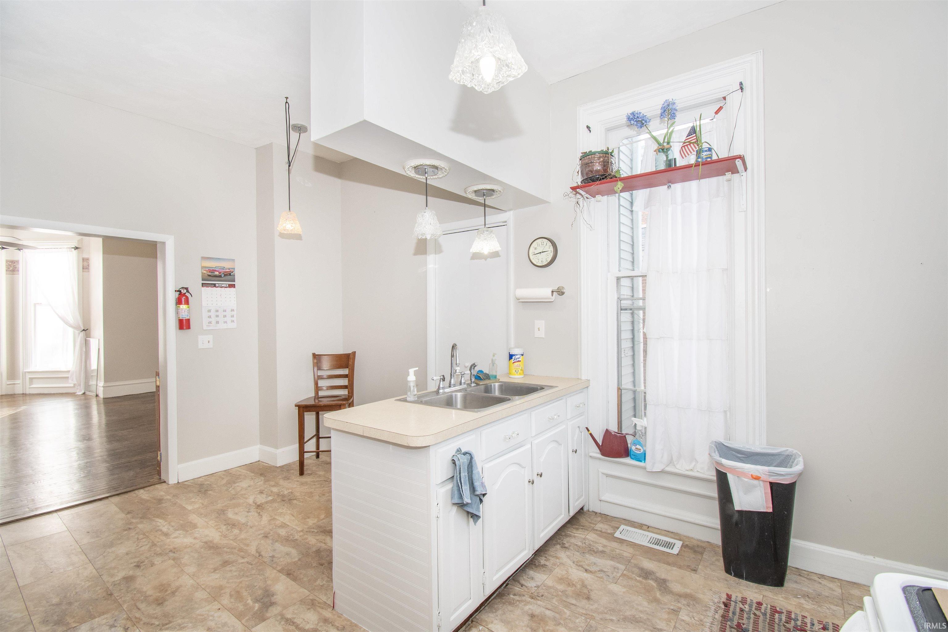 Kitchen featuring hanging light fixtures, light countertops, and white cabinetry