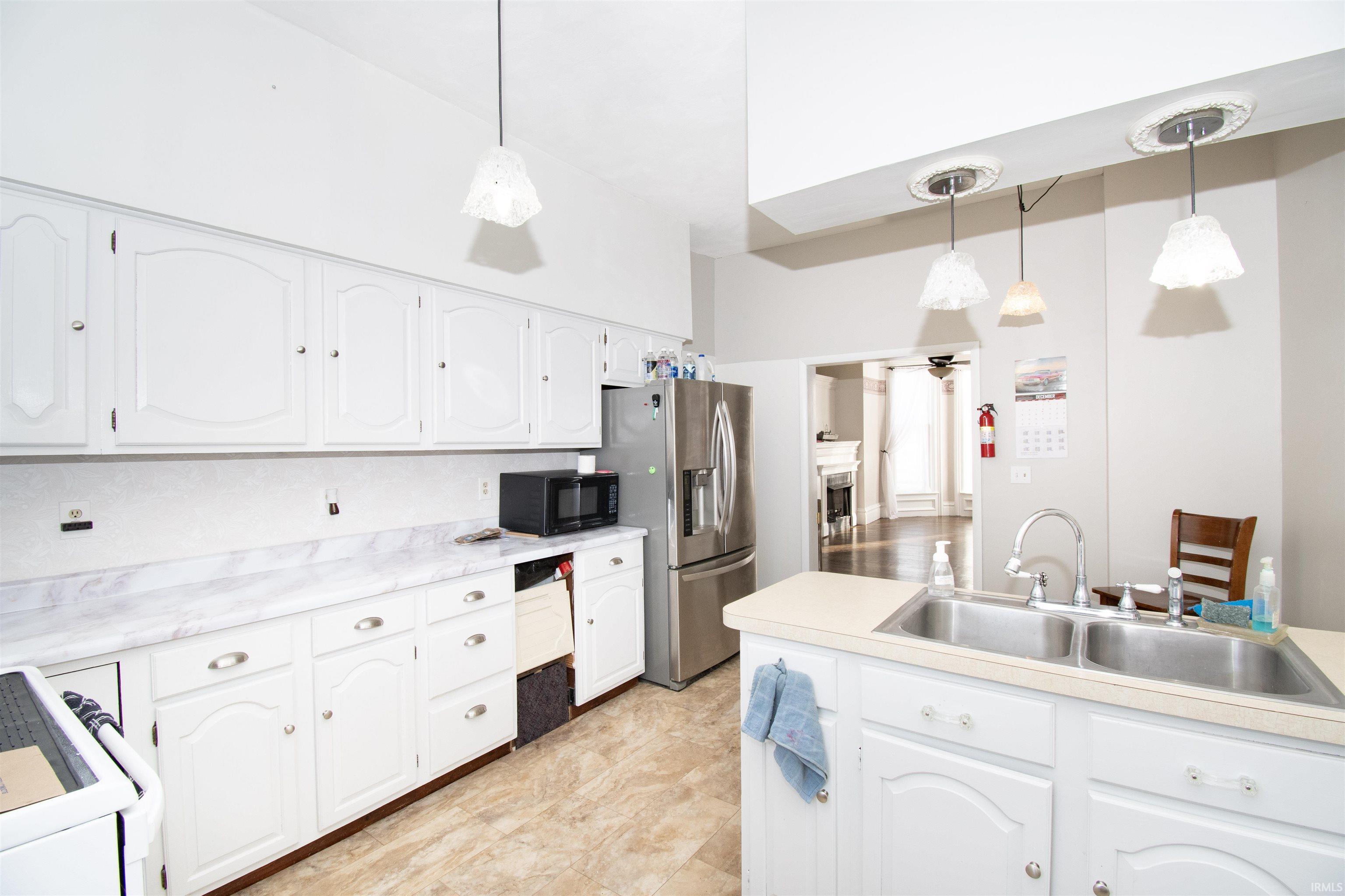 Kitchen featuring white cabinets, white range, light countertops, and hanging light fixtures
