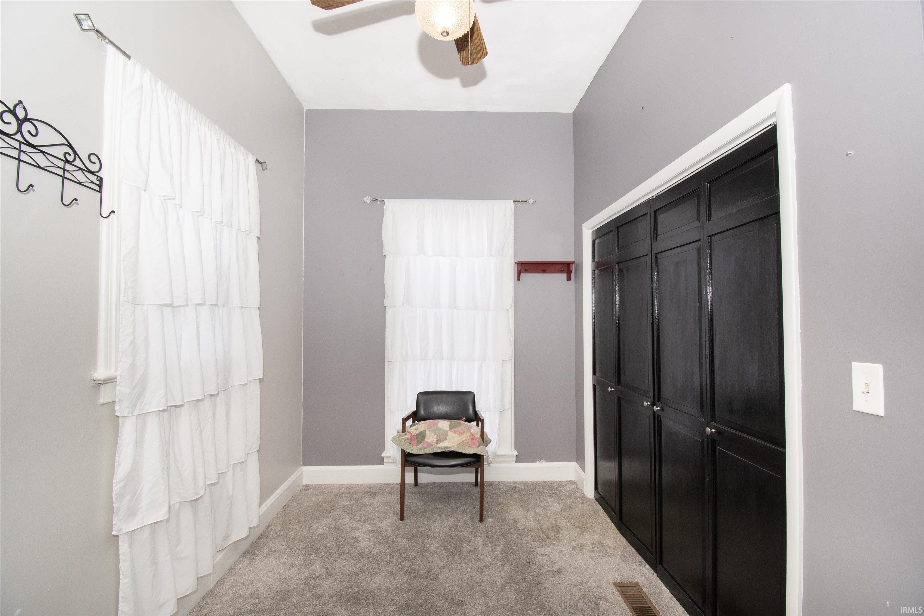 Living area featuring light colored carpet and ceiling fan