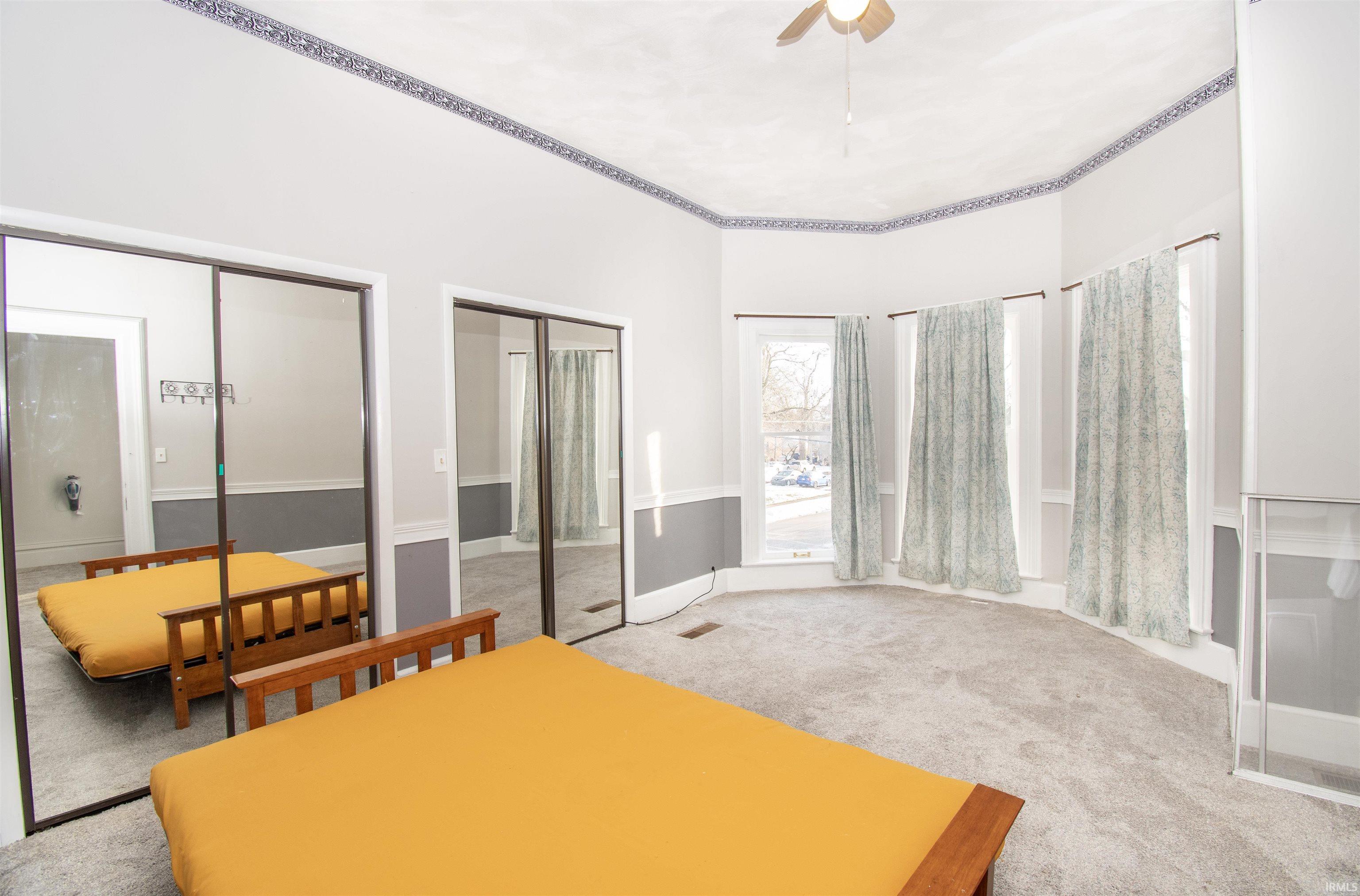 Bedroom featuring multiple closets, carpet flooring, and ceiling fan