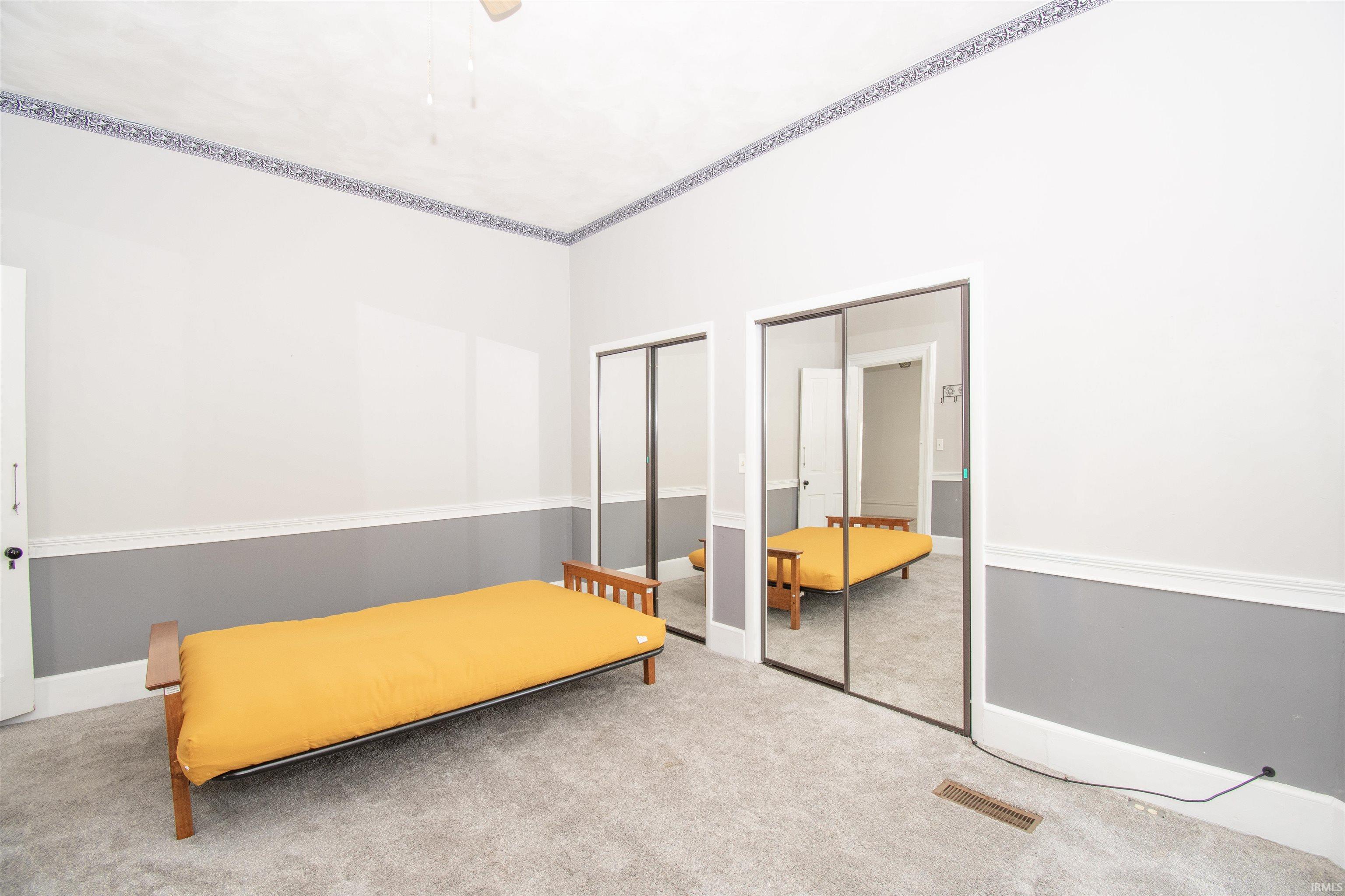 Carpeted bedroom with two closets and a ceiling fan