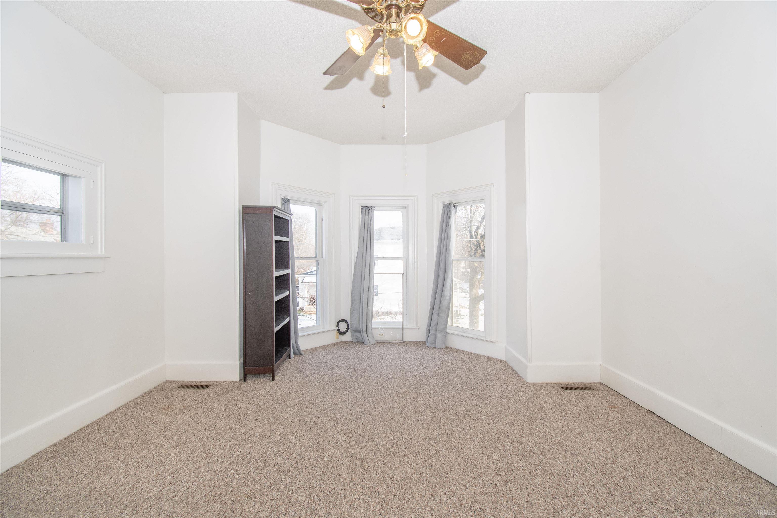 Spare room featuring light colored carpet and ceiling fan