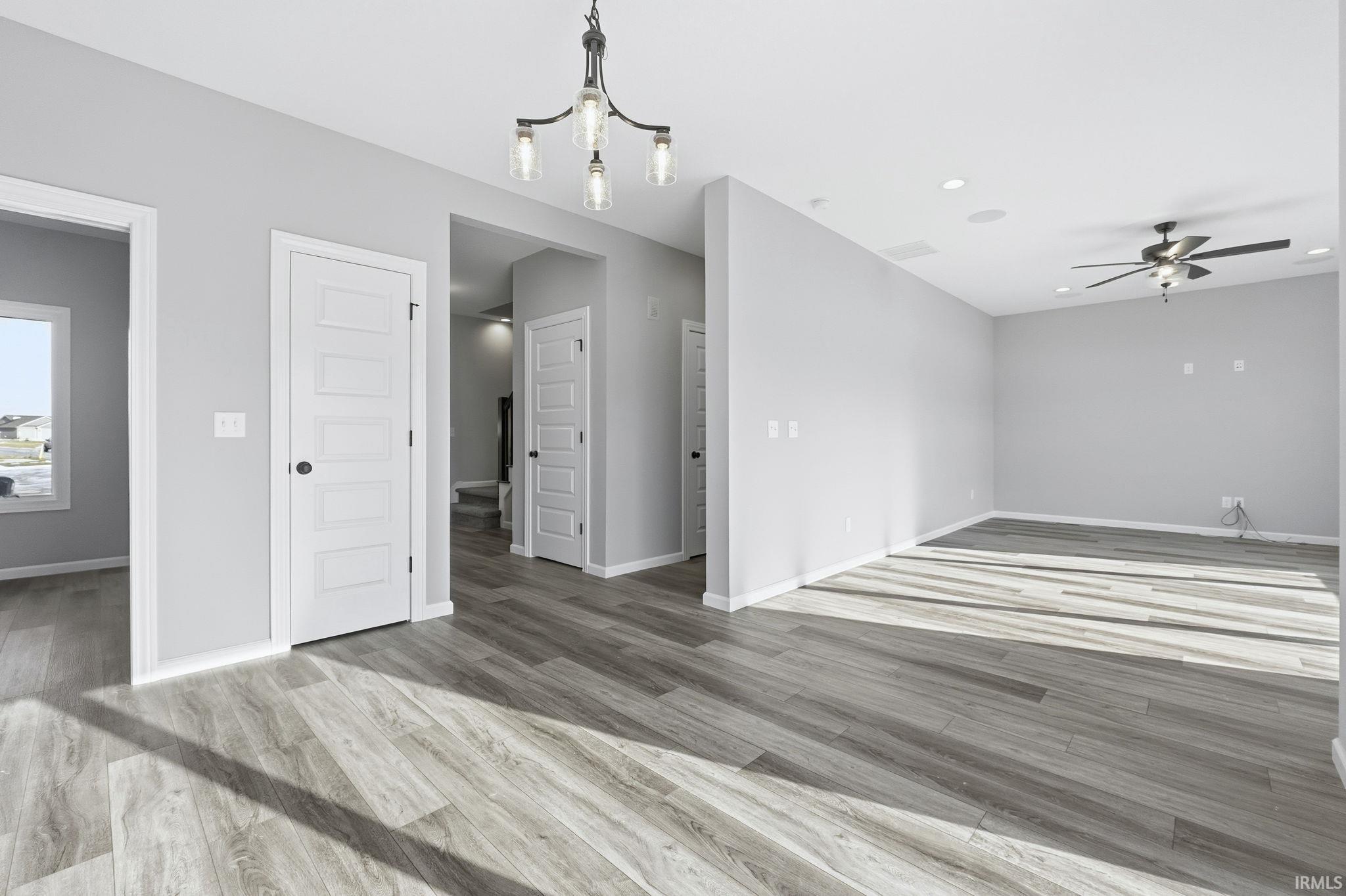 Unfurnished living room with a ceiling fan, a chandelier, light wood-style floors, and recessed lighting