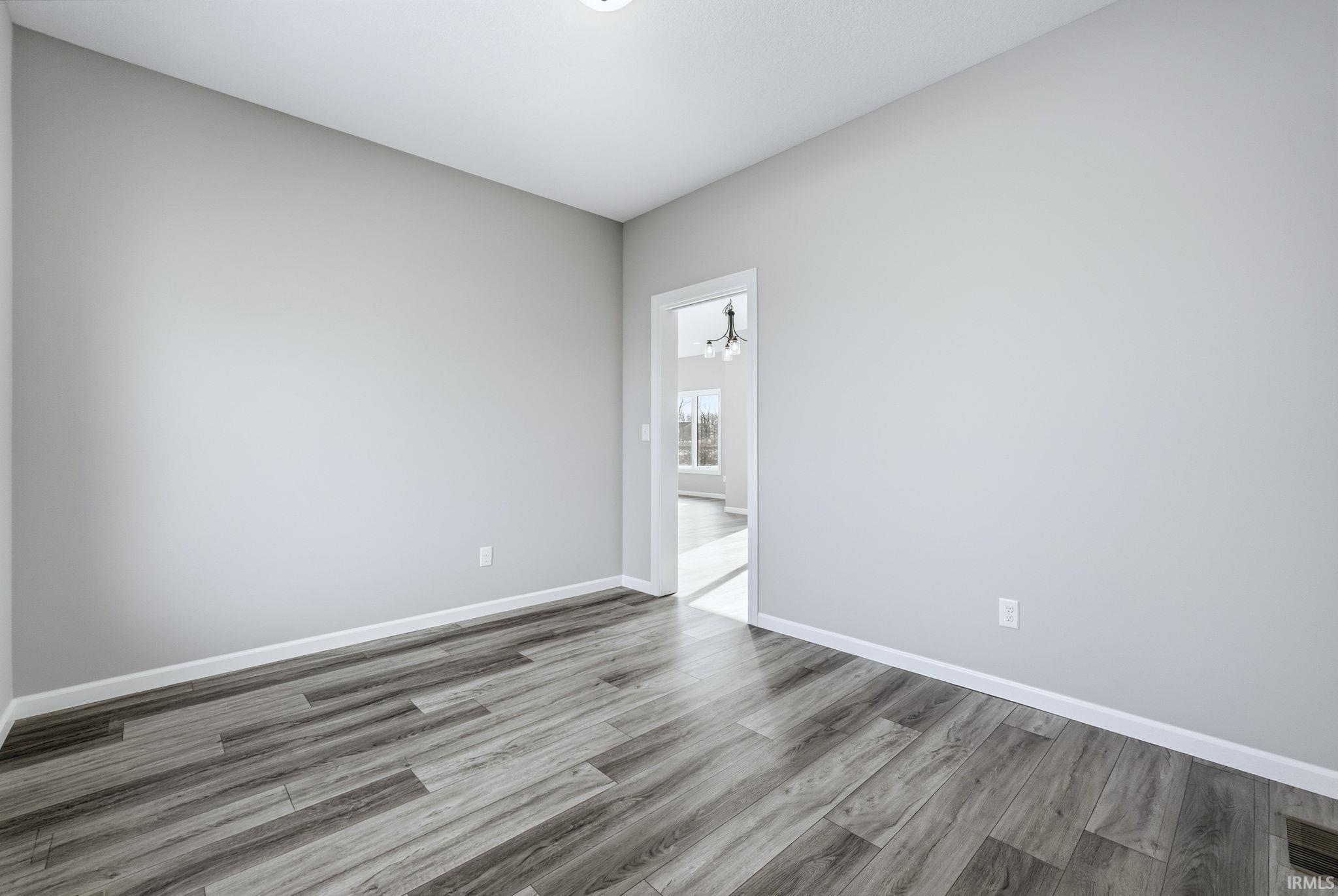 Spare room with wood finished floors and a chandelier