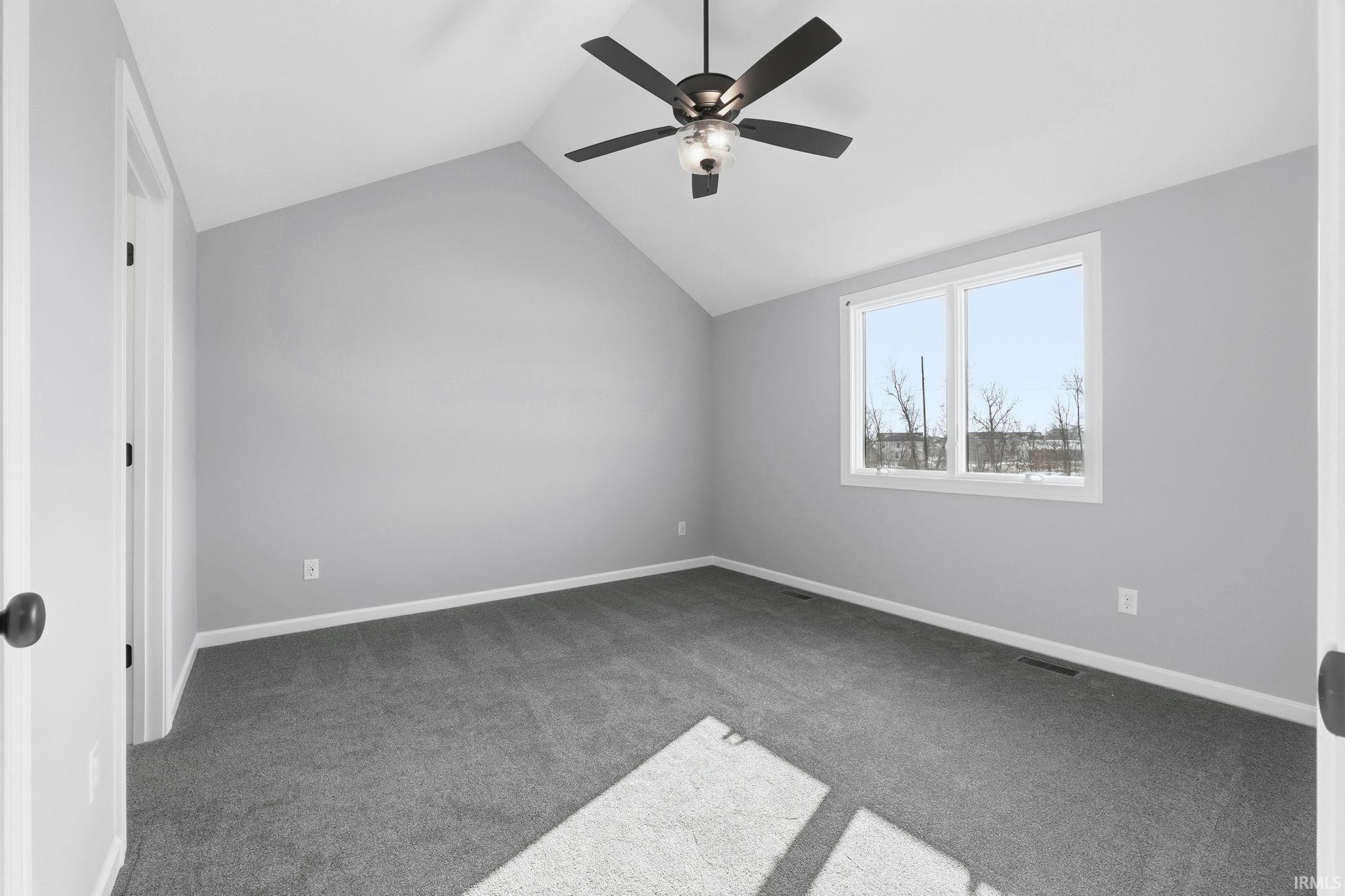 Additional living space featuring vaulted ceiling, carpet flooring, and a ceiling fan