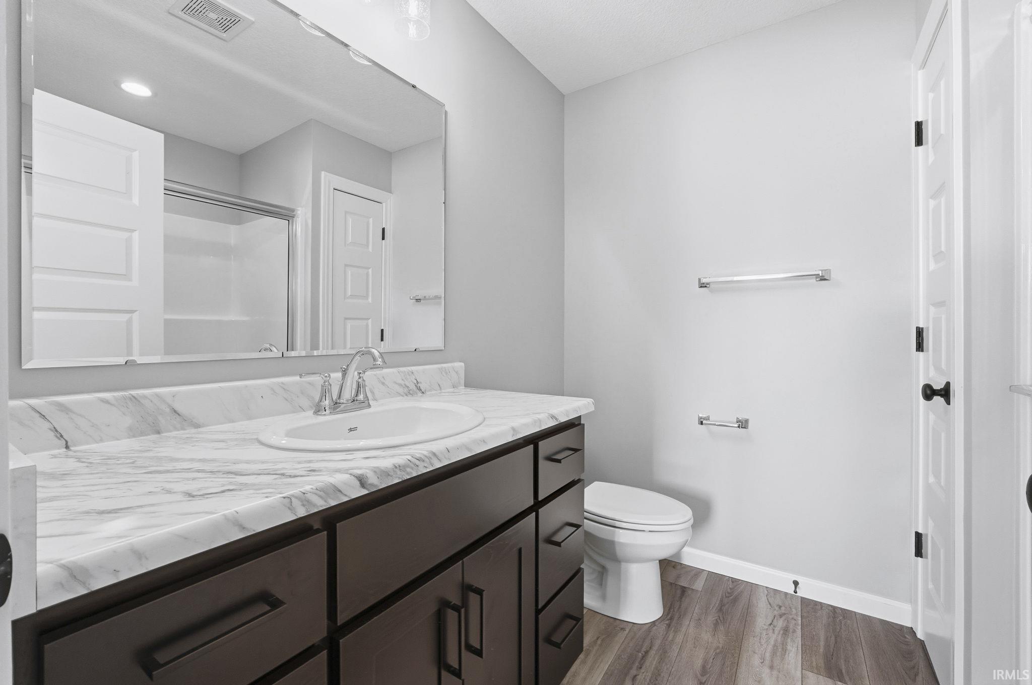 Bathroom with vanity, a shower with door, and dark wood-style flooring
