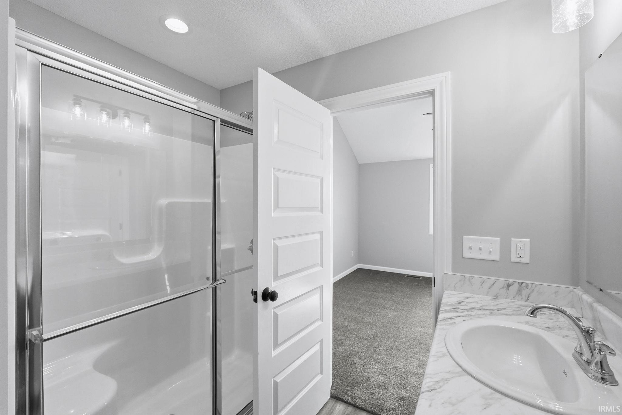 Bathroom featuring a stall shower, light carpet, vanity, and a textured ceiling