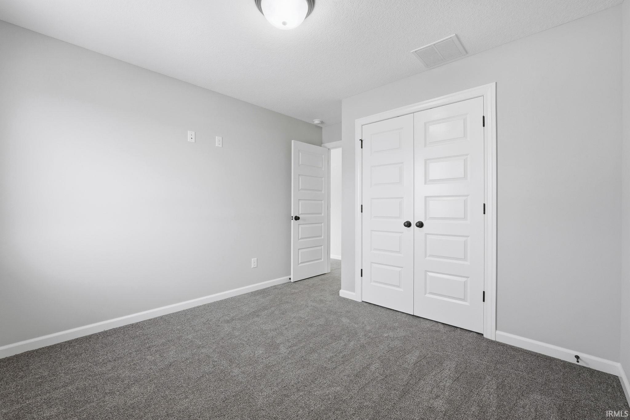 Unfurnished bedroom featuring a closet, carpet, and a textured ceiling