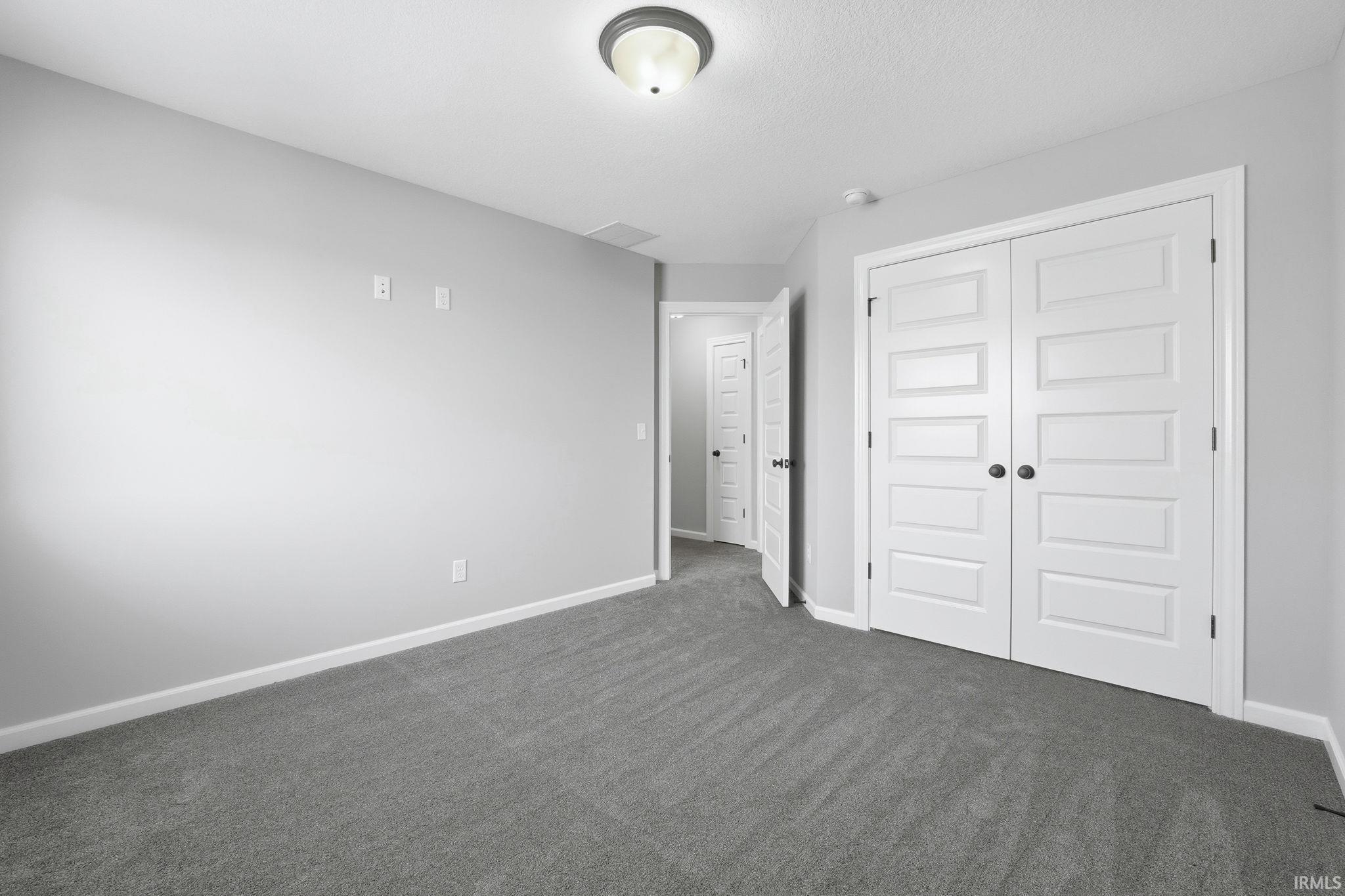 Unfurnished bedroom featuring a closet and dark carpet