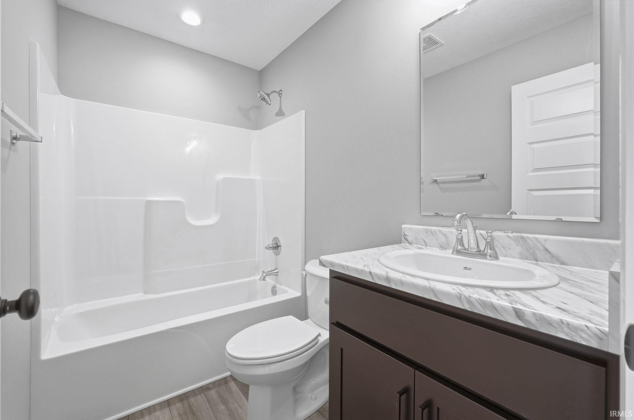 Full bath featuring vanity, shower / washtub combination, and light wood-type flooring