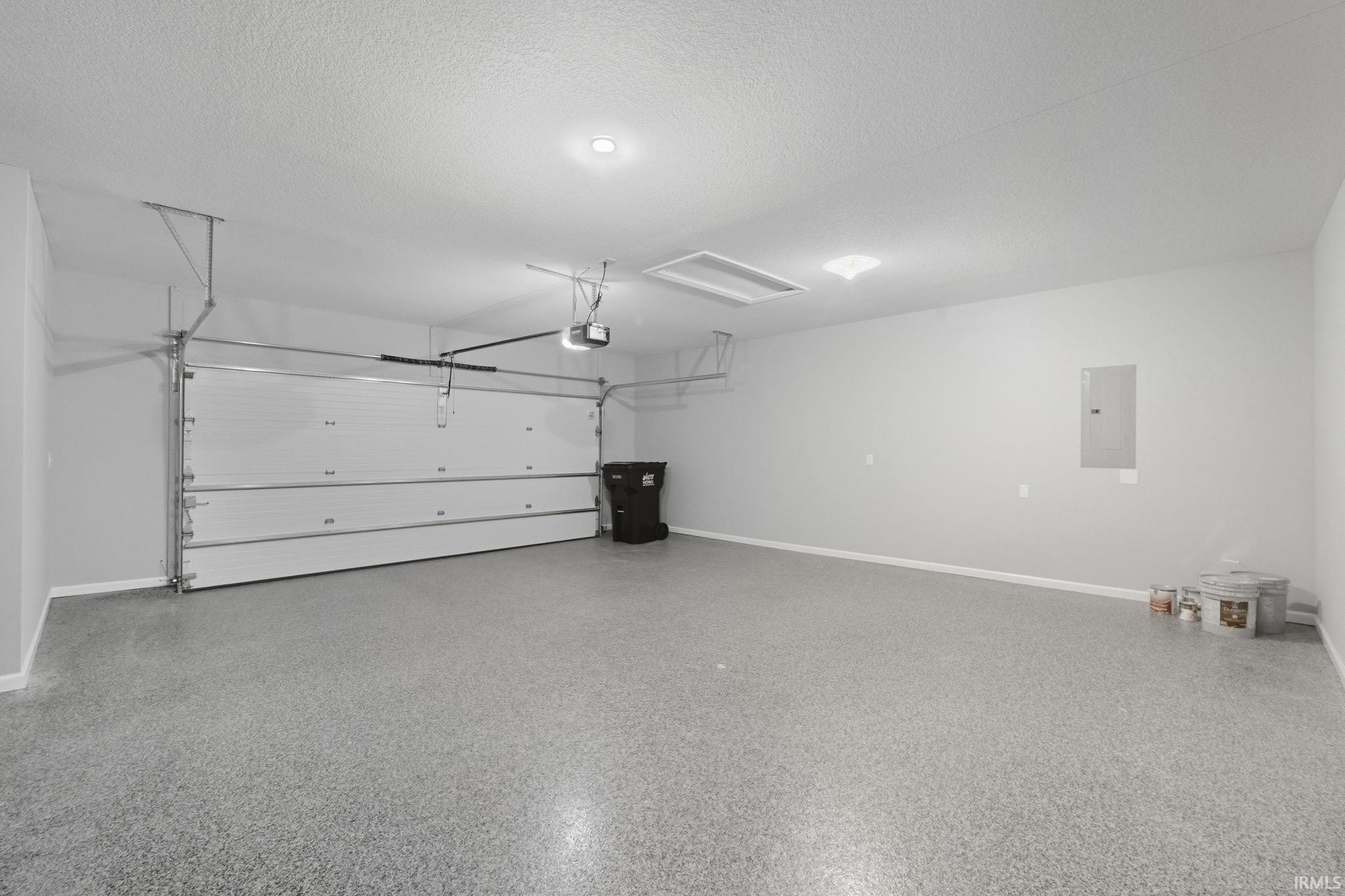 Garage featuring baseboards and electric panel
