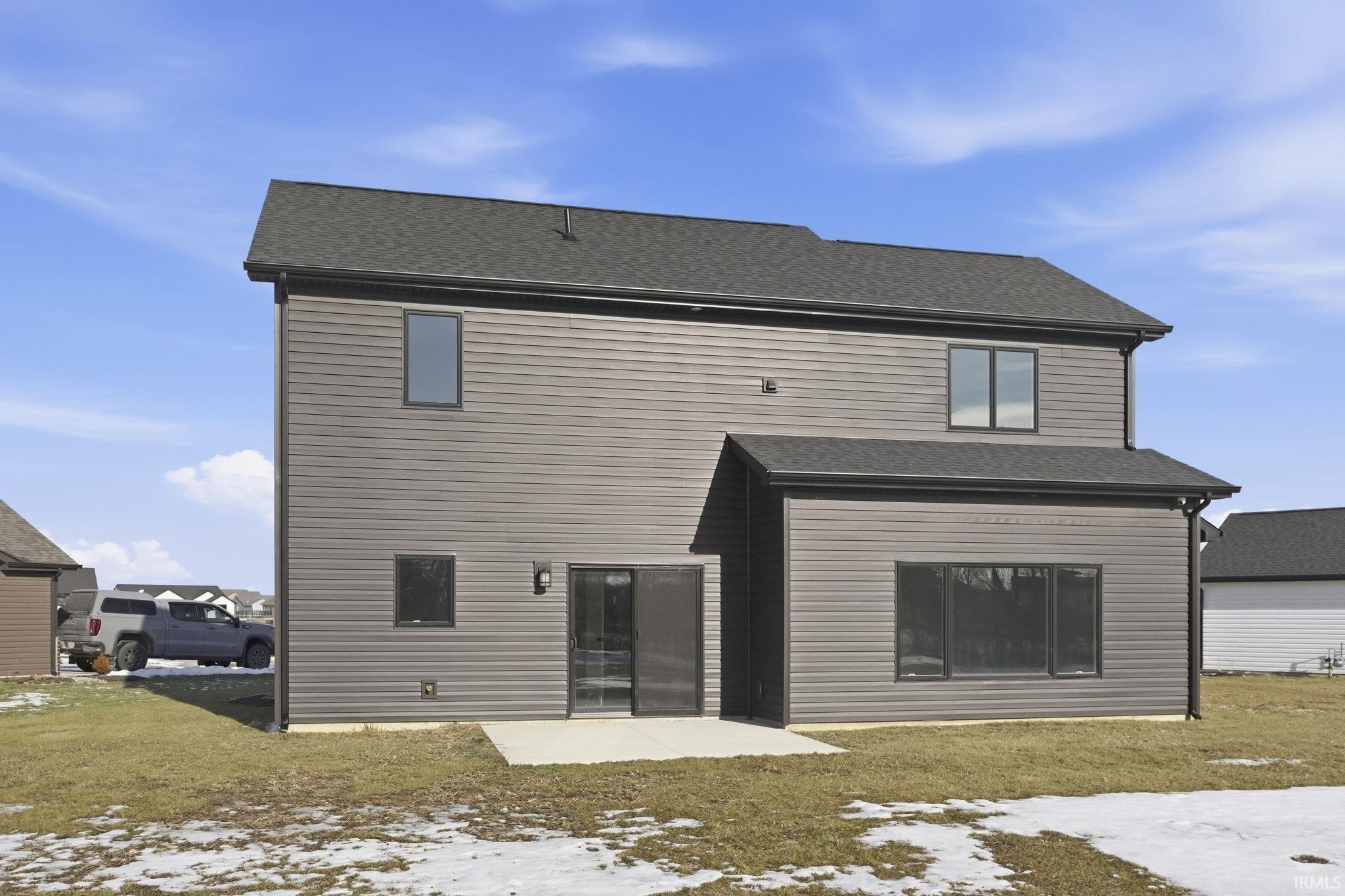 Snow covered property featuring a patio, a yard, and roof with shingles