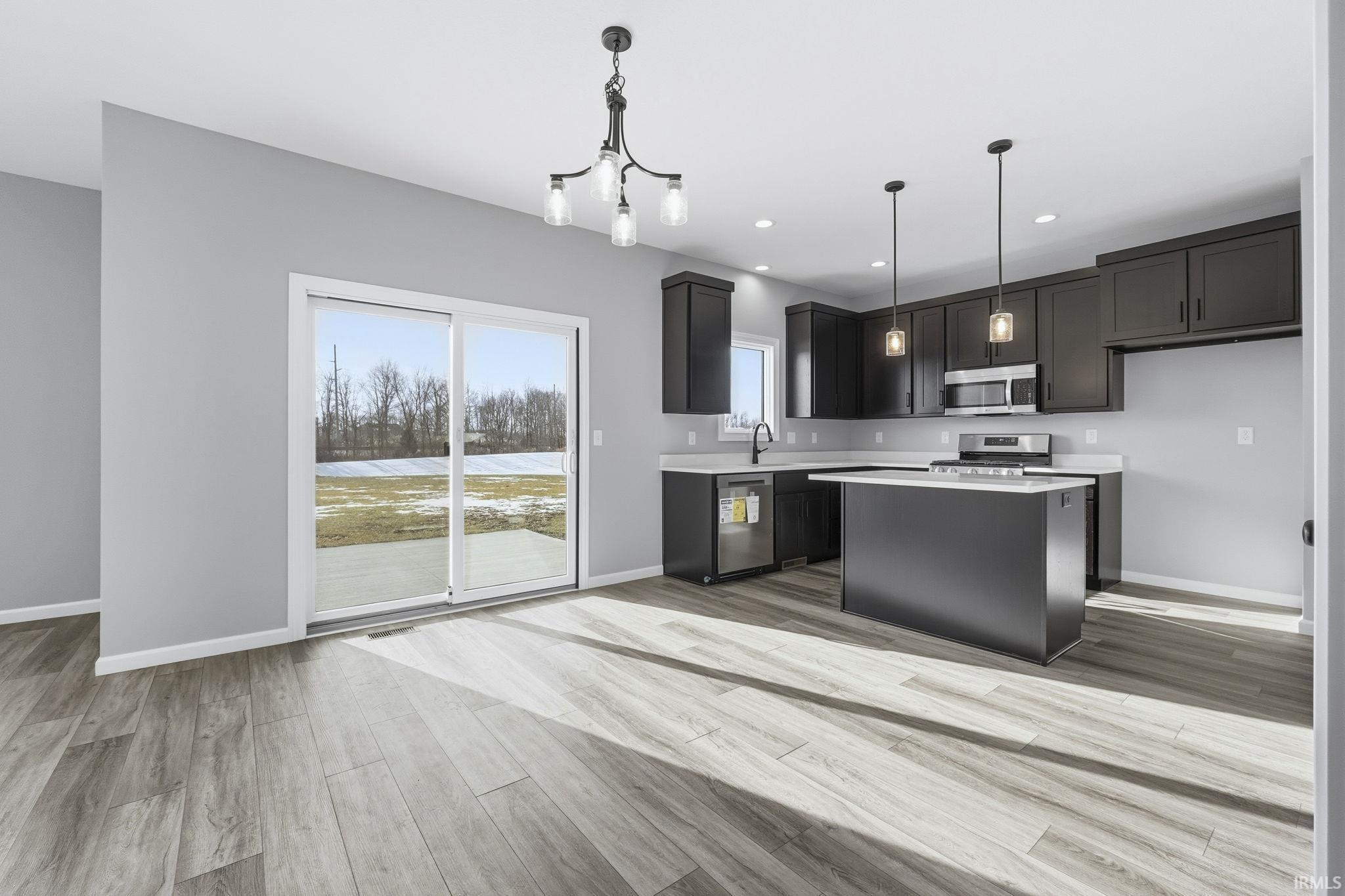 Kitchen featuring a kitchen island, hanging light fixtures, appliances with stainless steel finishes, light wood-style floors, and recessed lighting