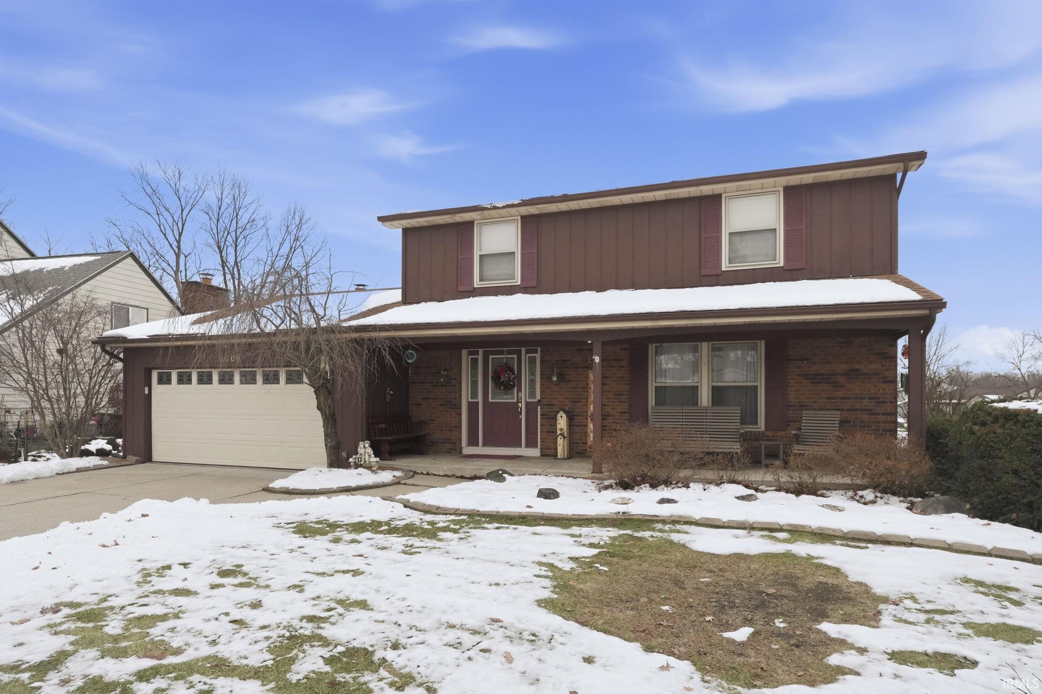 Traditional home featuring covered porch, an attached garage, concrete driveway, and brick siding