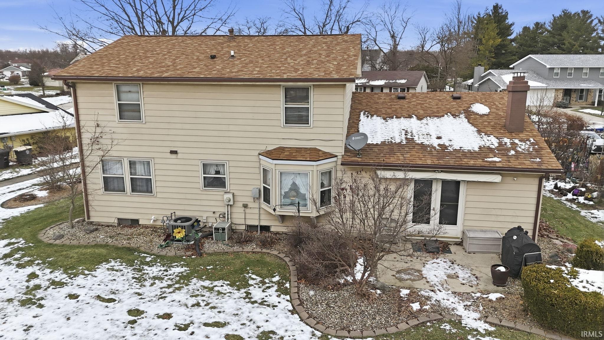 Snow covered rear of property with a chimney and a shingled roof