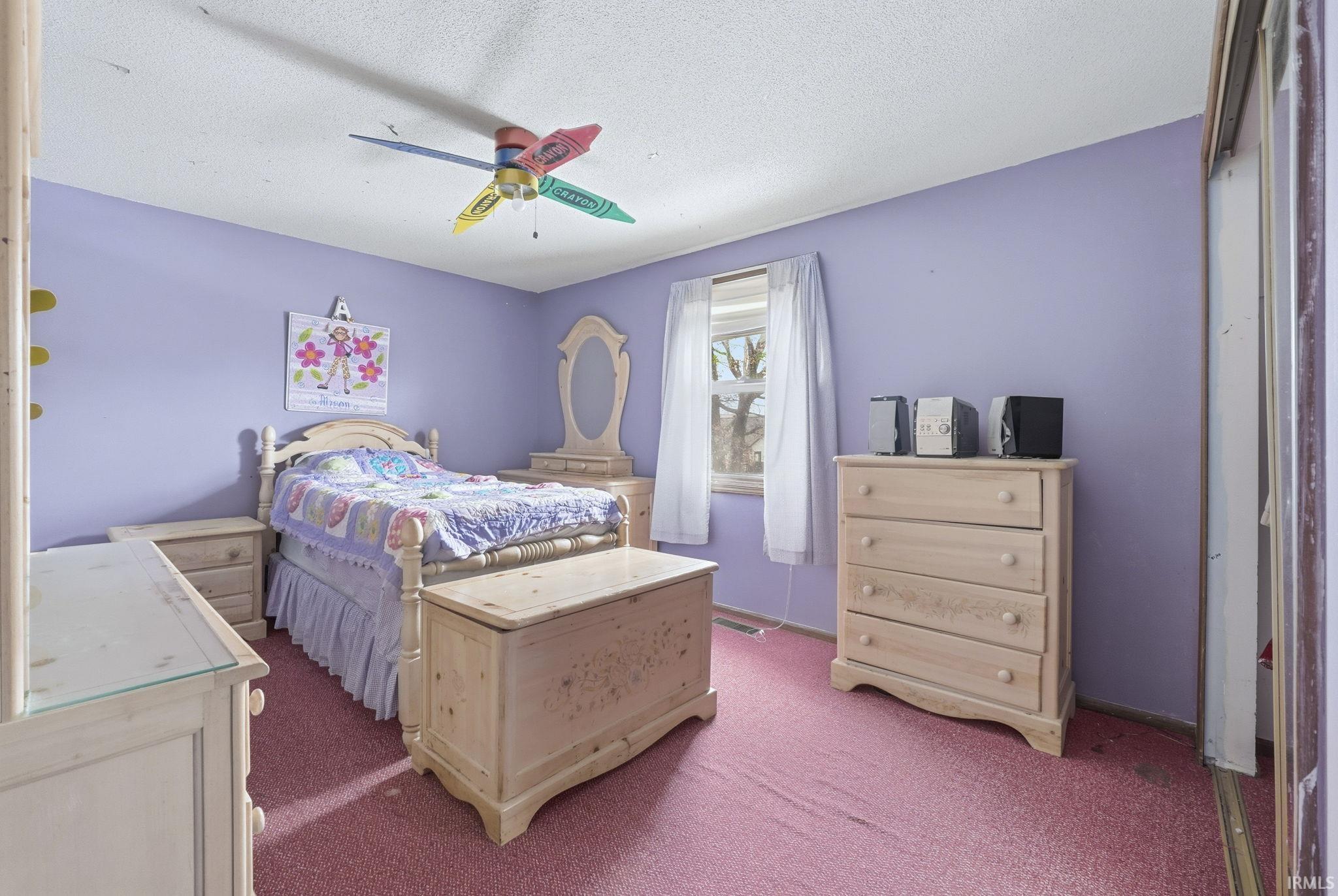 Bedroom with a textured ceiling, carpet floors, and a ceiling fan