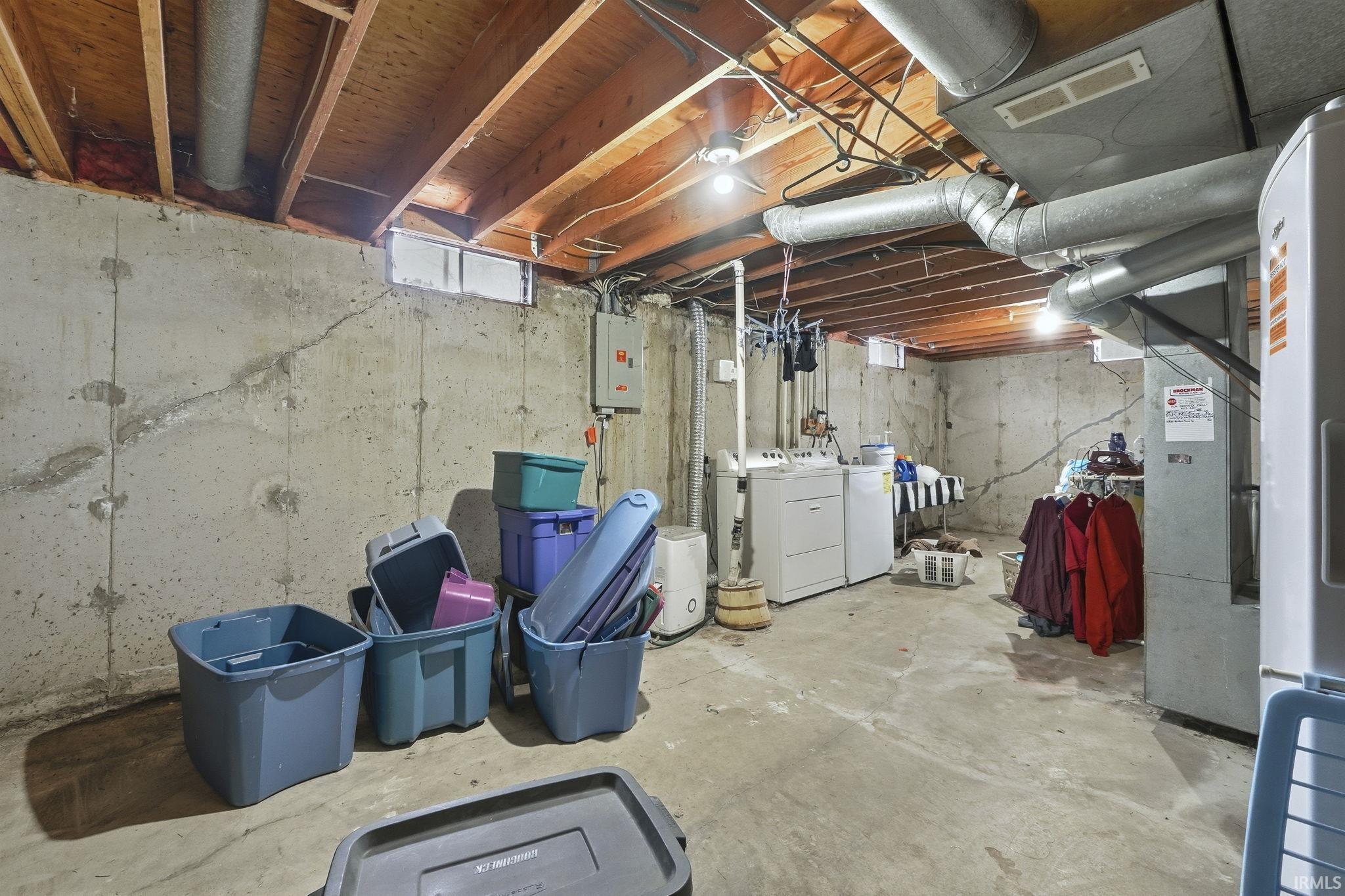 Unfinished below grade area with washing machine and clothes dryer