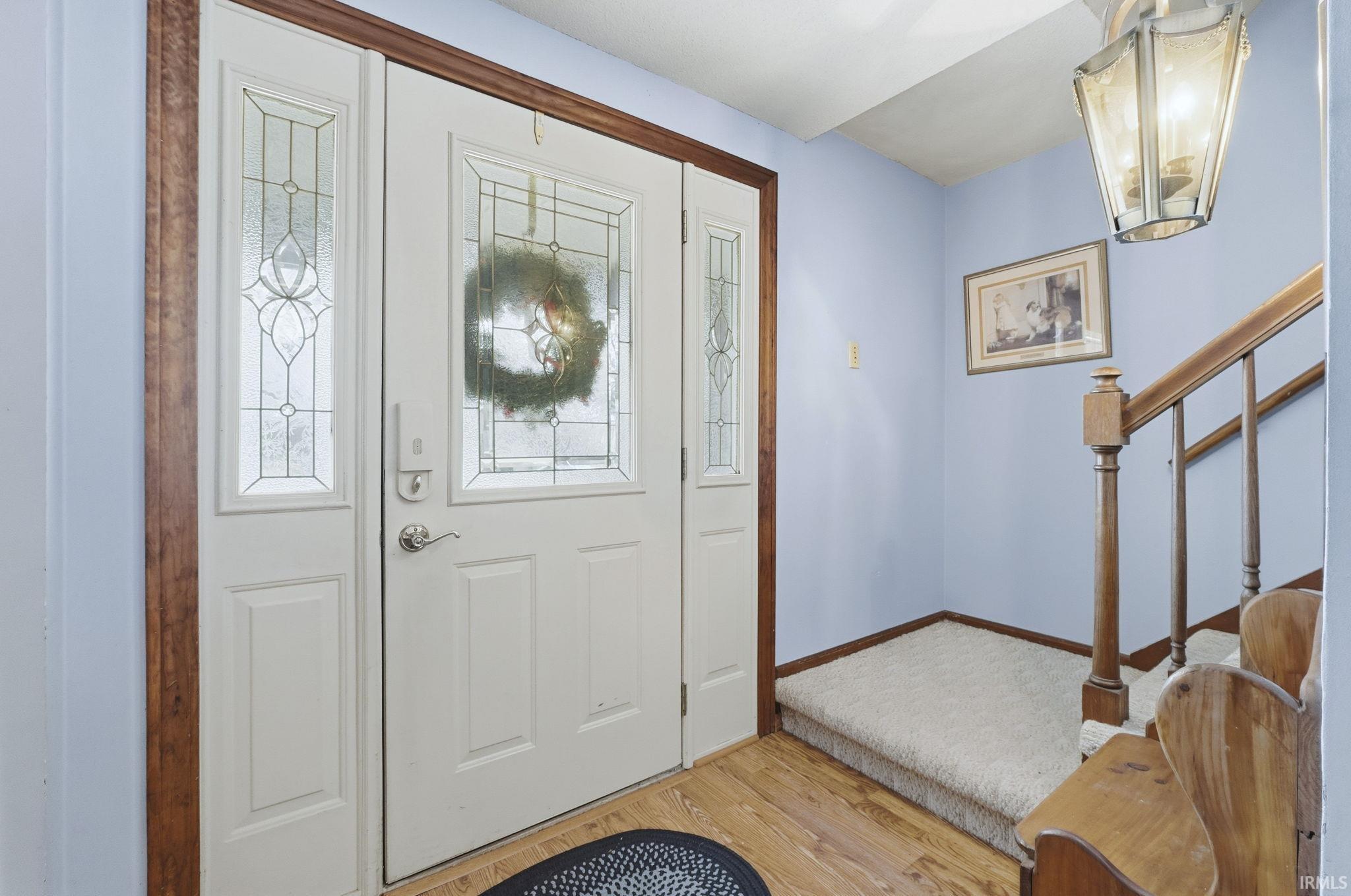 Foyer entrance with stairs, light wood-style floors, and a chandelier