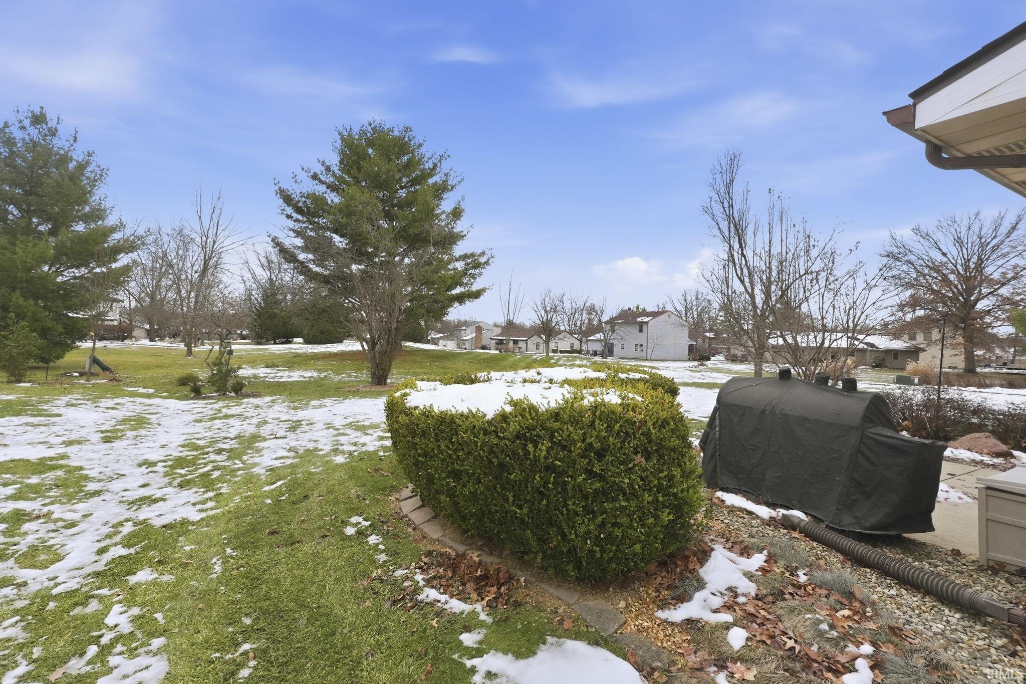Yard layered in snow featuring a lawn