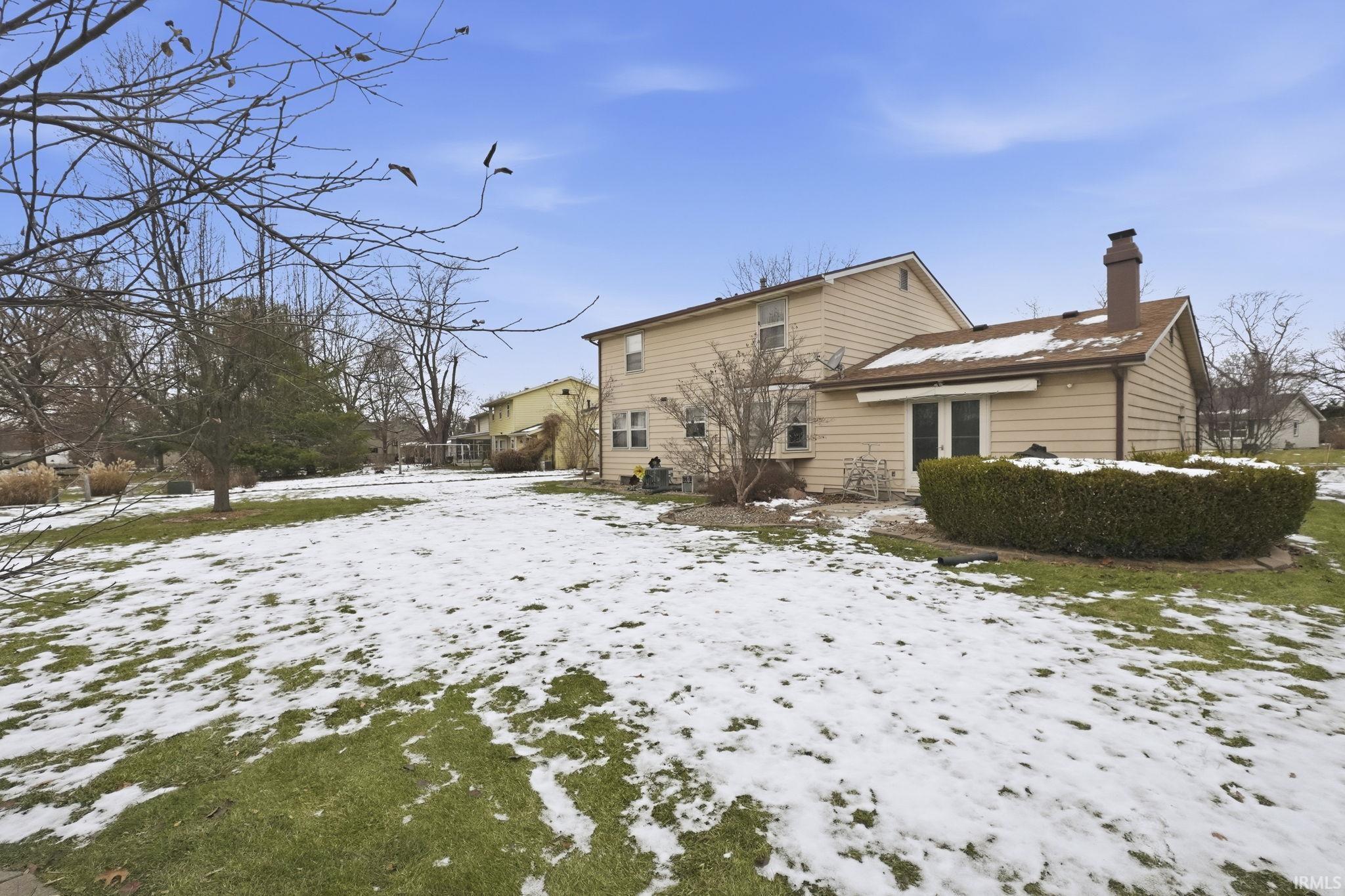 Snow covered rear of property with a chimney