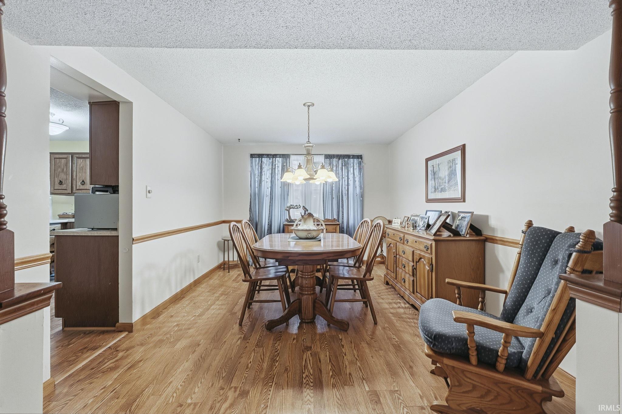 Dining room with light wood-style floors, a textured ceiling, and a chandelier