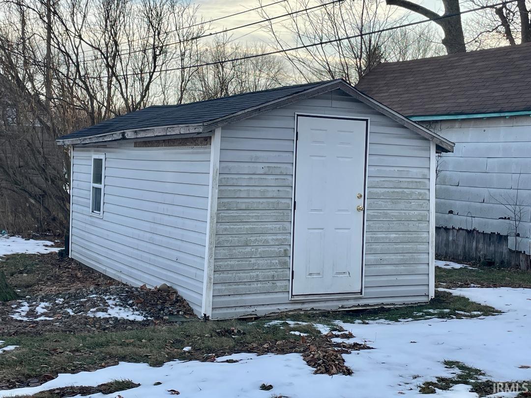 Snow covered structure featuring a storage unit