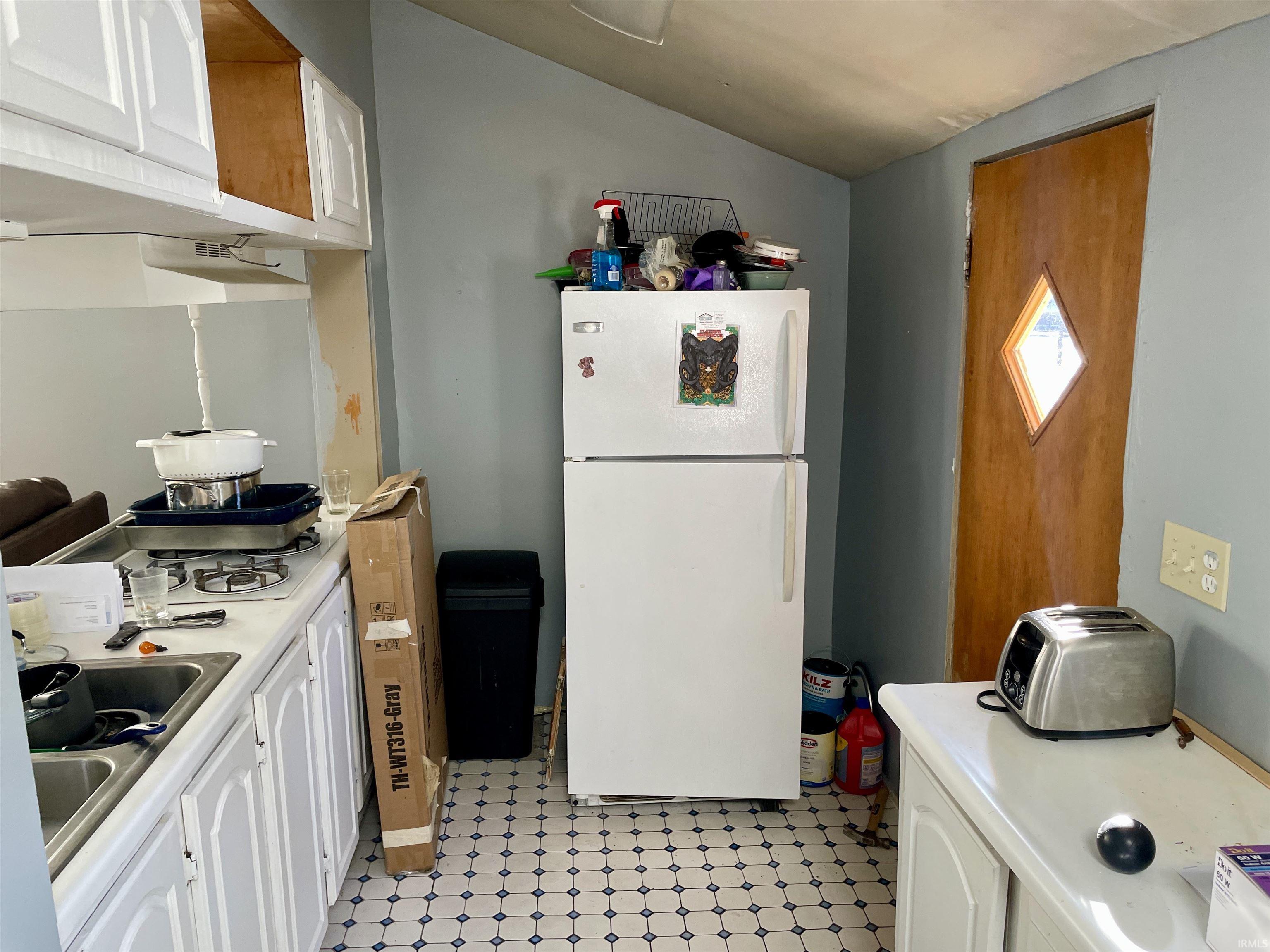 Kitchen featuring white cabinets, light flooring, light countertops, and white appliances