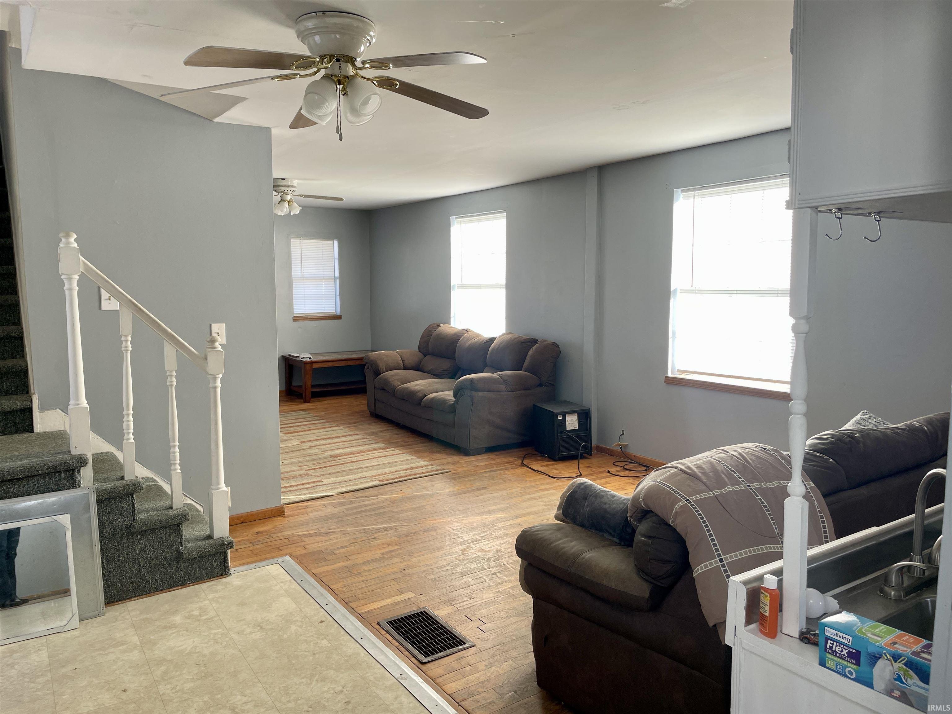 Living room featuring stairs, ceiling fan, and light wood-style floors