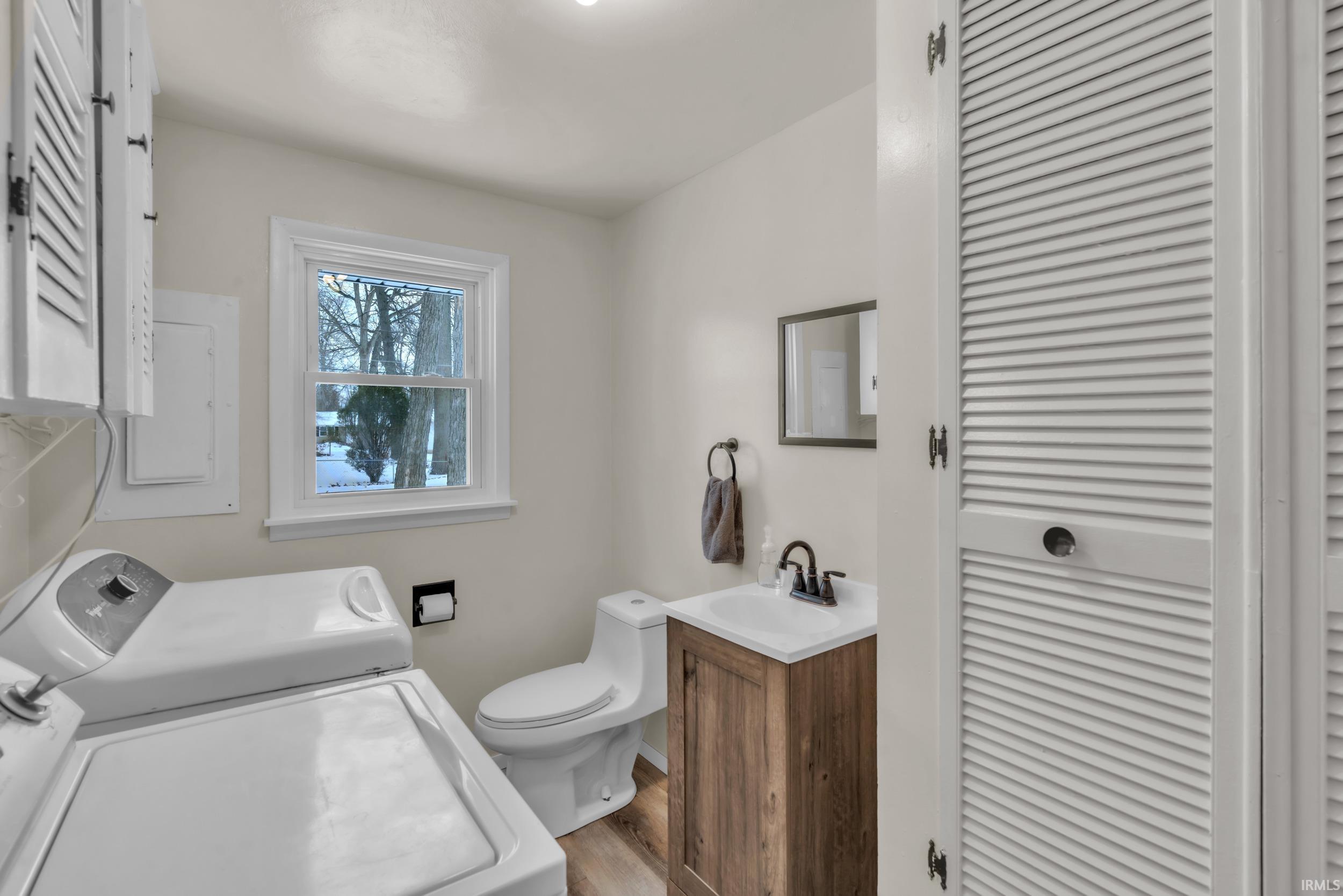 Bathroom featuring a closet, vanity, electric panel, and light wood-style flooring