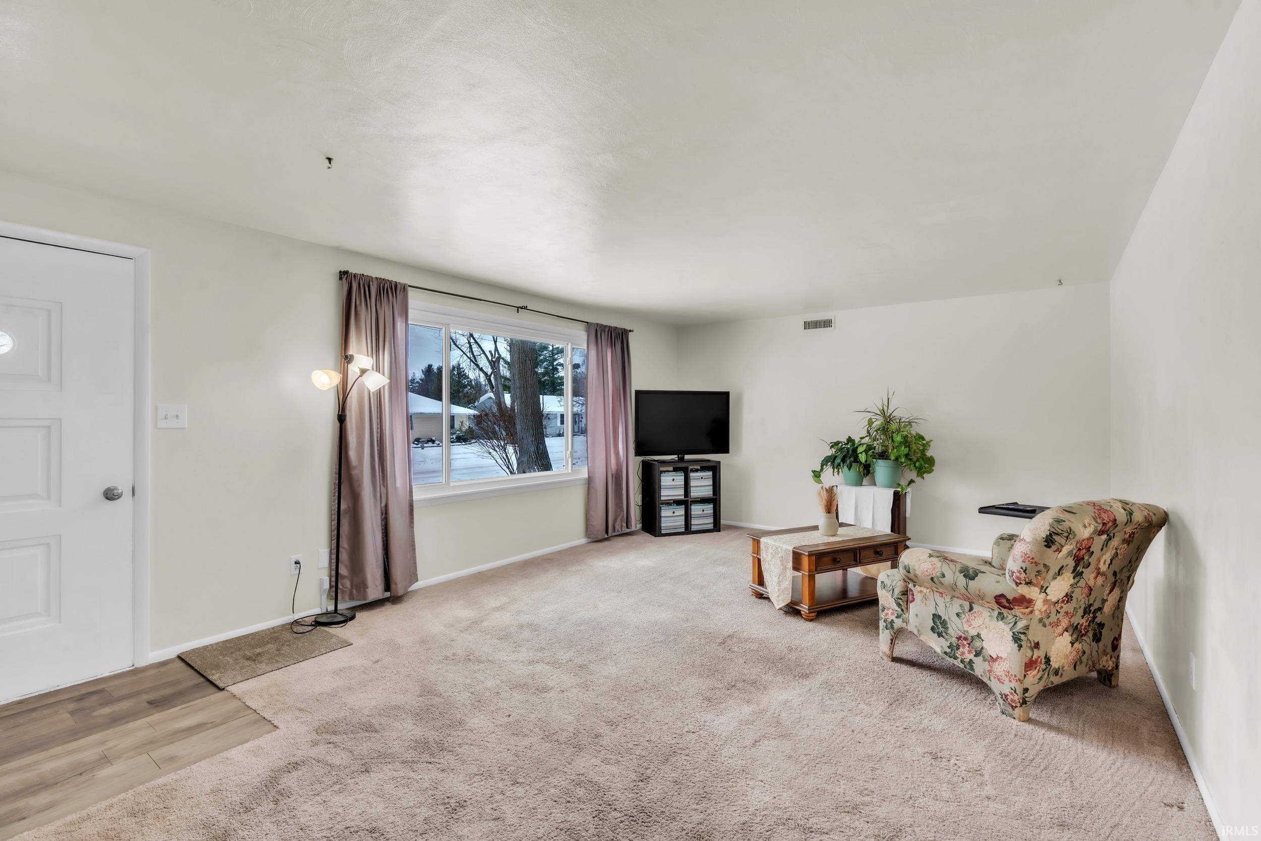 Living area featuring baseboards and light colored carpet