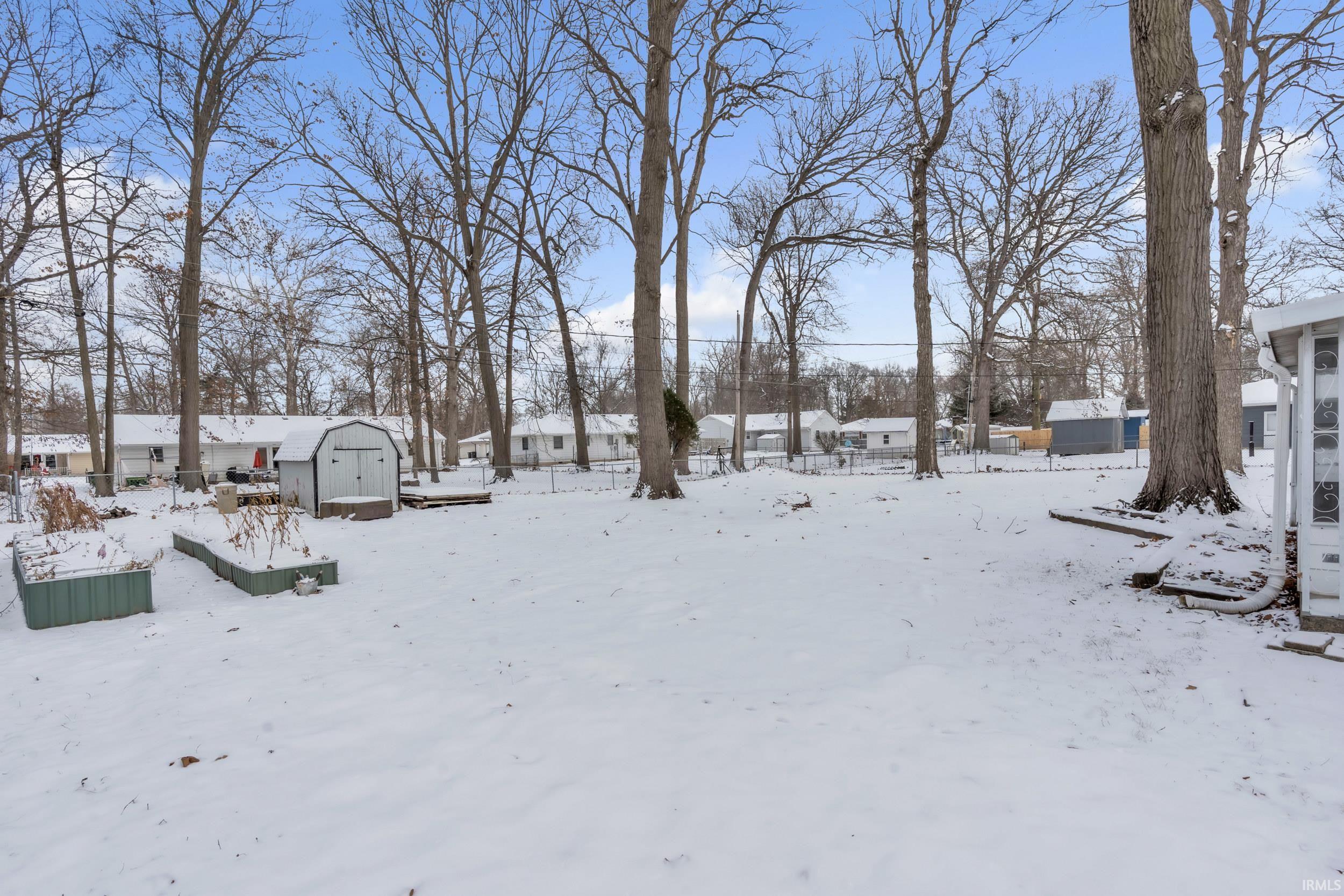 Yard covered in snow featuring a storage shed