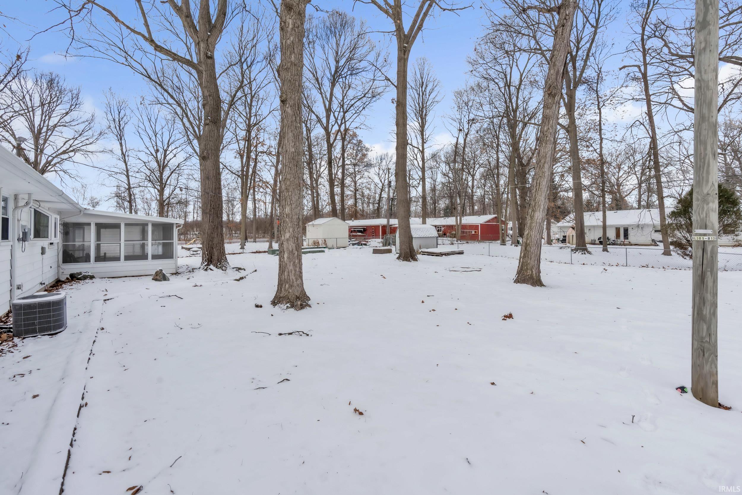 Yard layered in snow featuring a sunroom