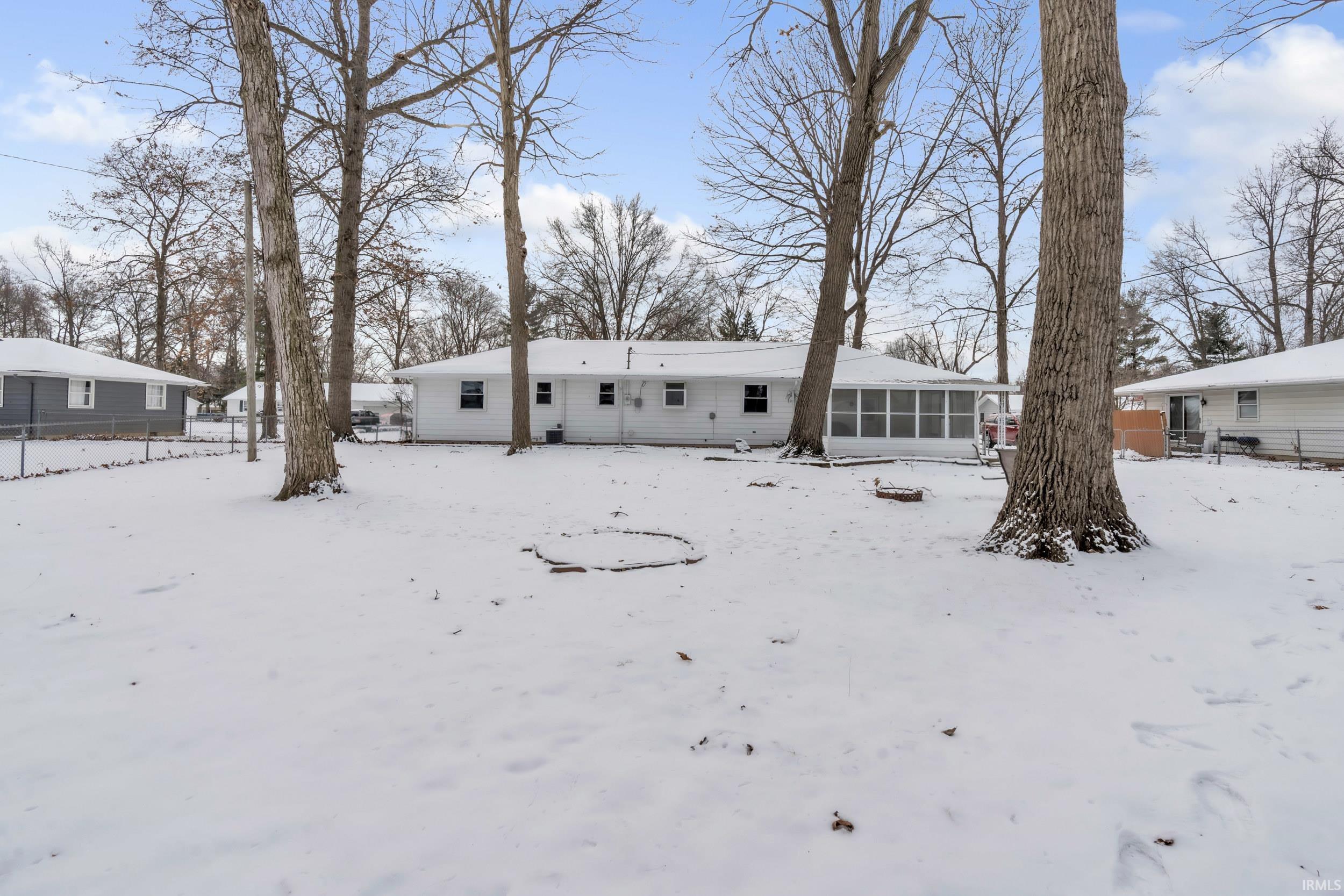 Snow covered rear of property with a sunroom